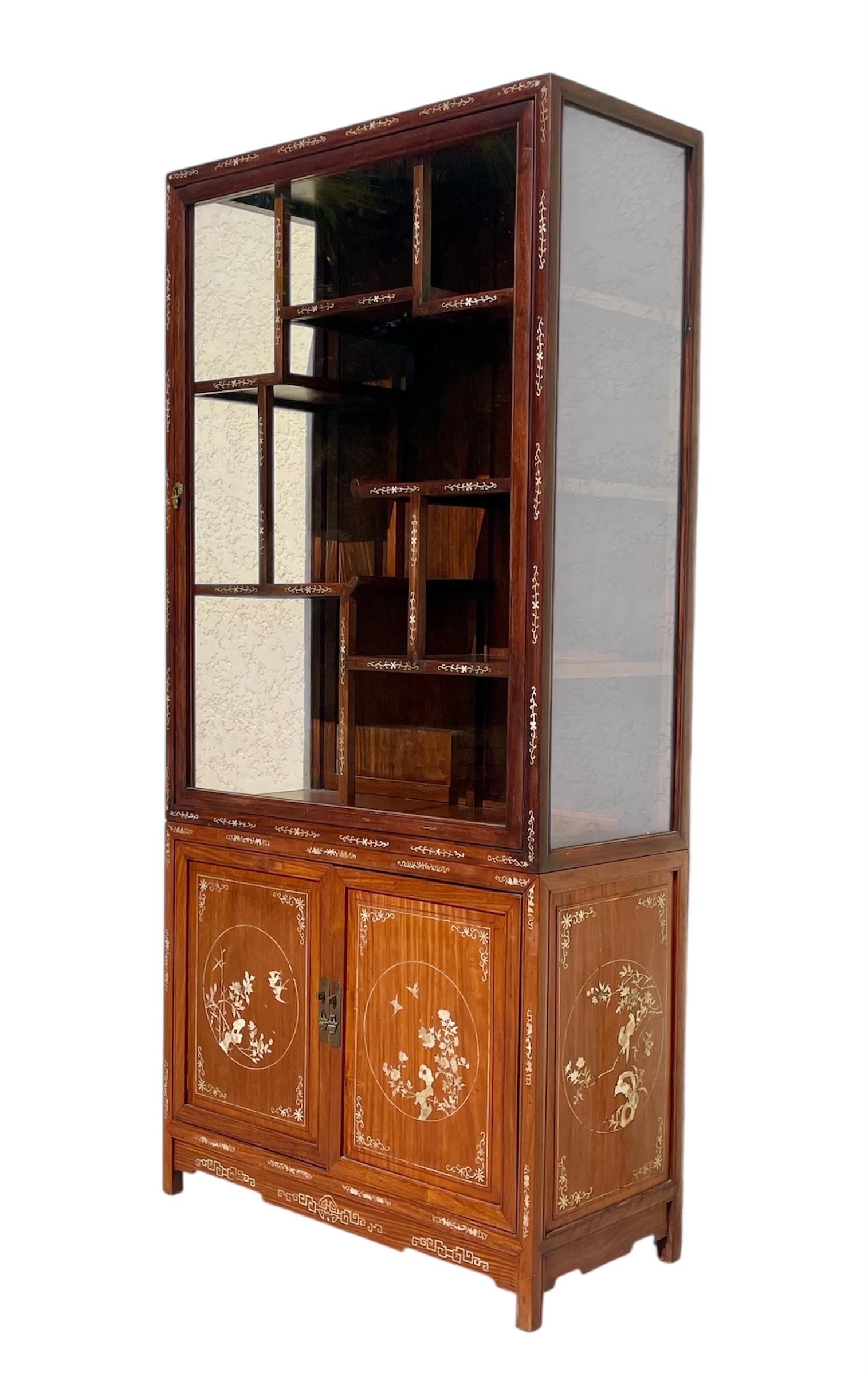 Sehr schöne Vitrine im asiatischen Stil mit floralen Perlmuttverzierungen. Diese Vitrine öffnet sich oben mit einer Glastür und unten mit zwei Türen, die als Schrank dienen. Diese Vitrine ist in gutem Zustand. Er kann in zwei Teile zerlegt werden. 
