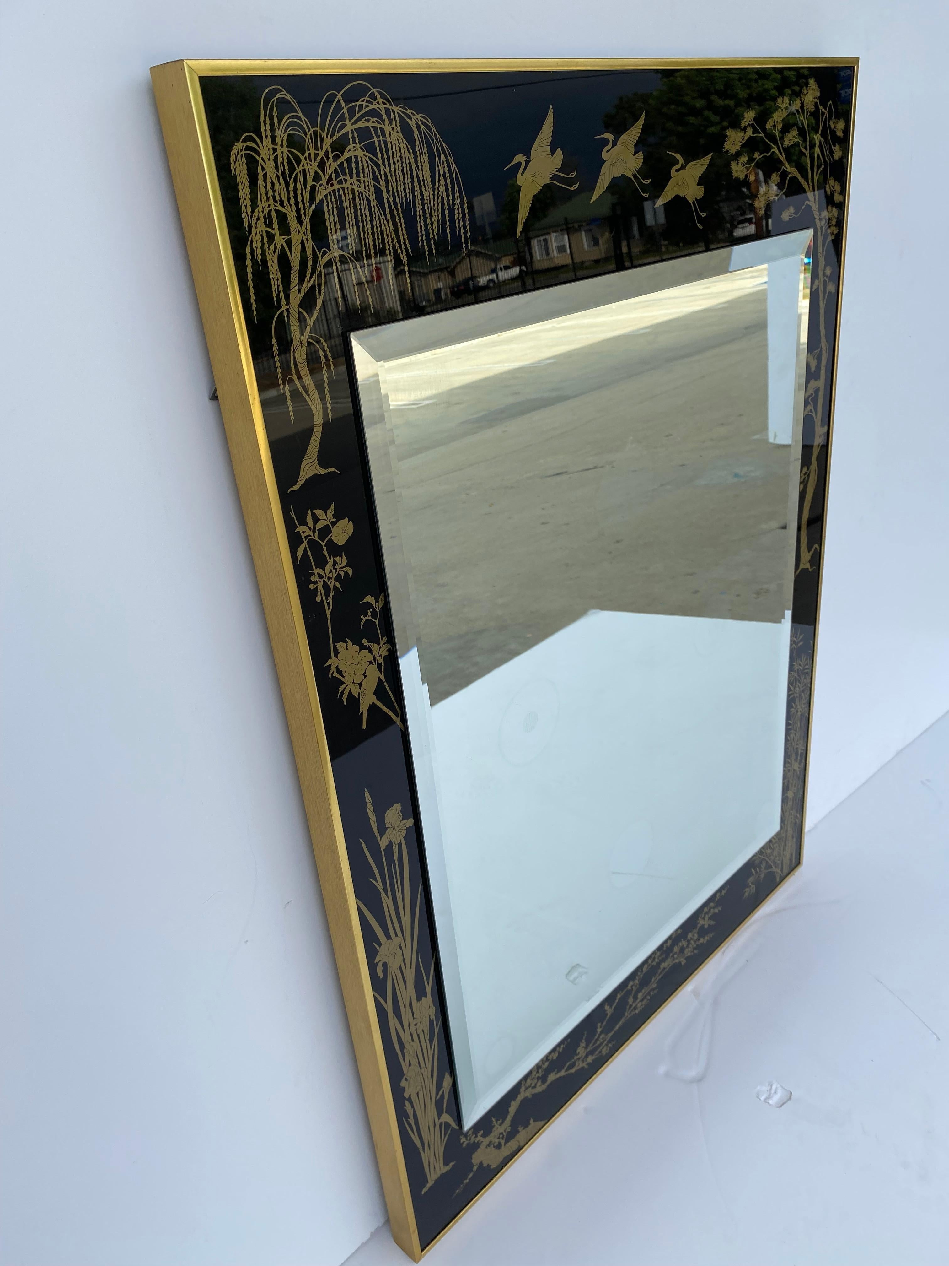 Black glass with a chinoiserie gold pattern of birds and trees with a mirror in the center.