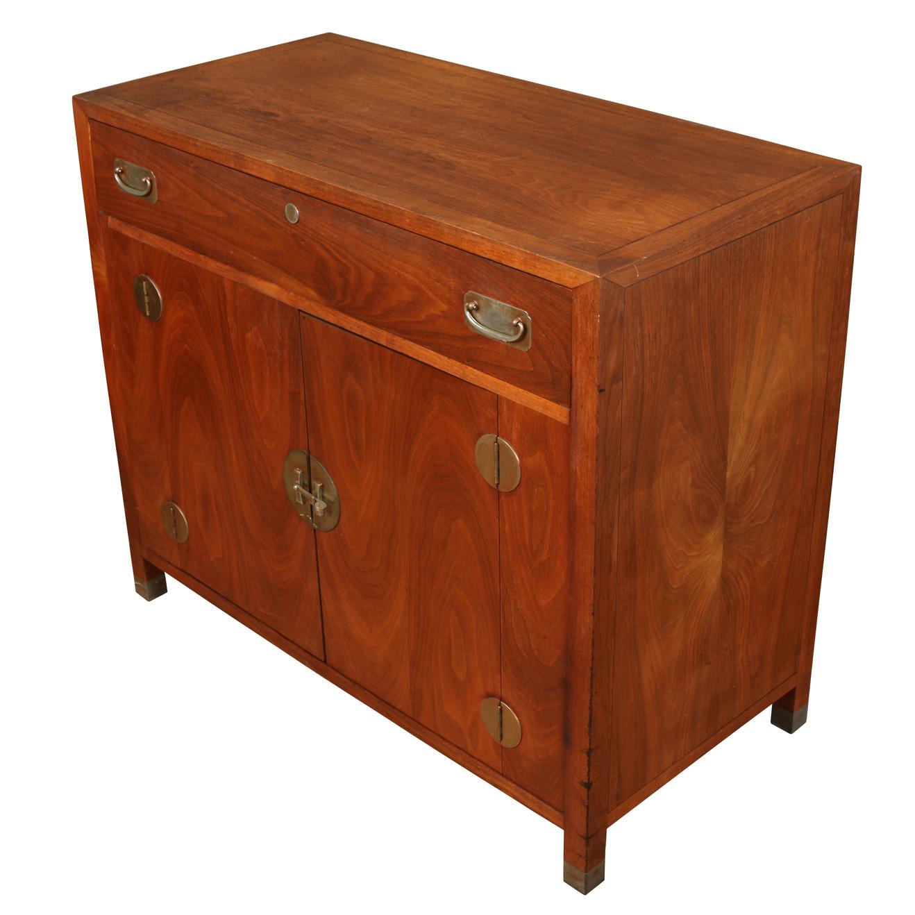 An Asian style walnut cabinet with brass details. The cabinet can be used as a server with a single drawer at top and two doors below that open to reveal two shelves.