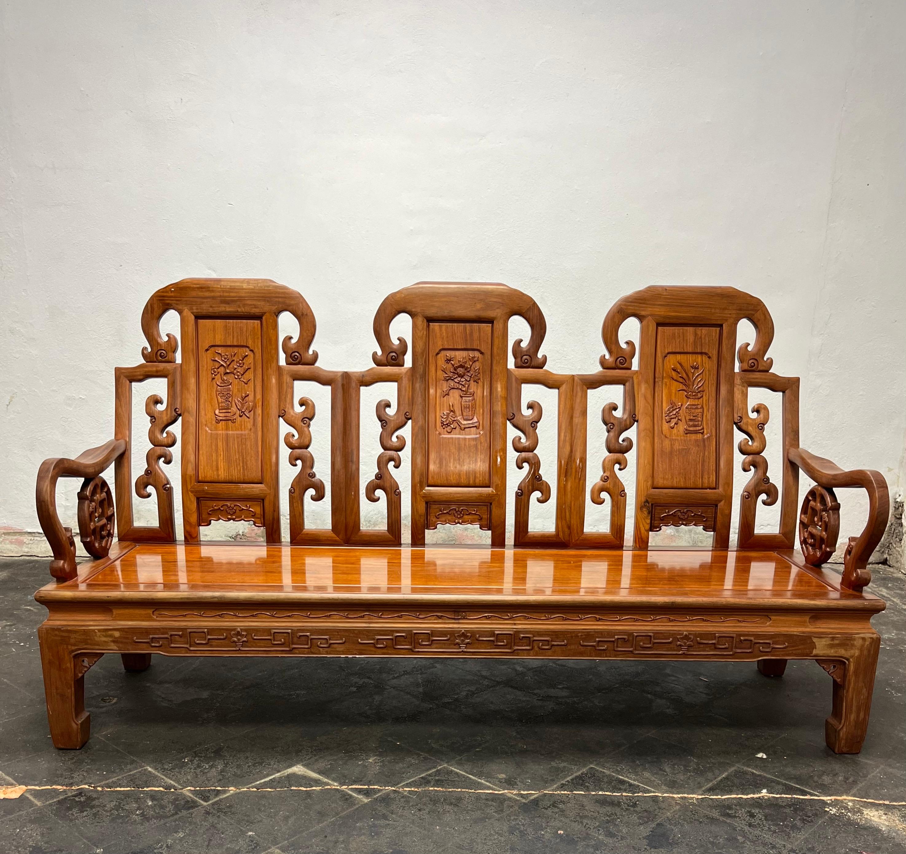 Beautiful chinoiserie sofa in the manner of George Zee.  3 high back shields. Ornate carvings of flower plant and palms. Highly decorated side shields, sweeping arms and platform style seat. Teak and Rosewood. Picture reflect color variance when