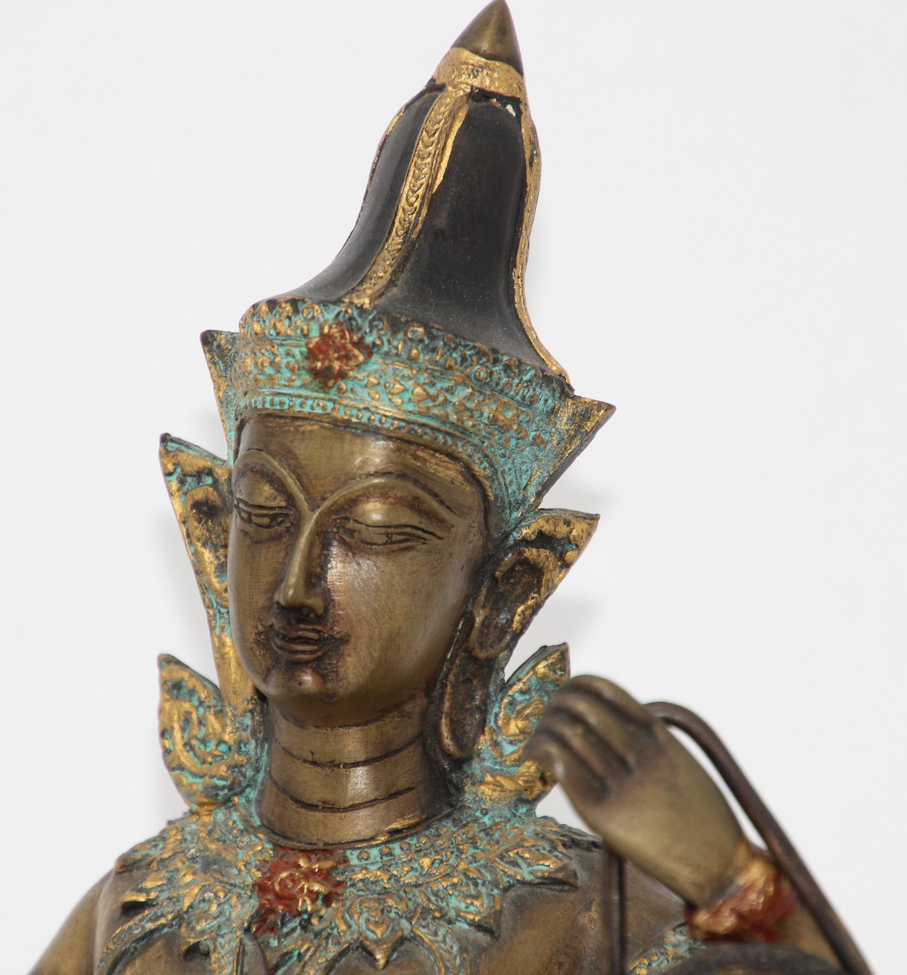 Asian gilt cold painted bronze statue of Prince Pra Apai Manee playing a traditional Asian instrument.
Intricate cast bronze Angel Buddha figure with gold leaf detailing wearing the ceremonial costume in green jade and jewelry are adorned with gold