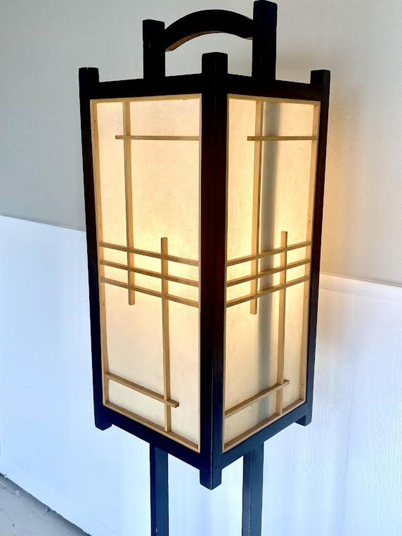 Asiatische quadratische Stehlampe aus Holz aus der Mitte des 20. Jahrhunderts, mit Reispapierplatten, die durch ein Gittermuster gesichert sind. Die Innenseite verbirgt die Steckdose. Die Oberseite besteht aus einem Holzgriff, der den Zugang zum