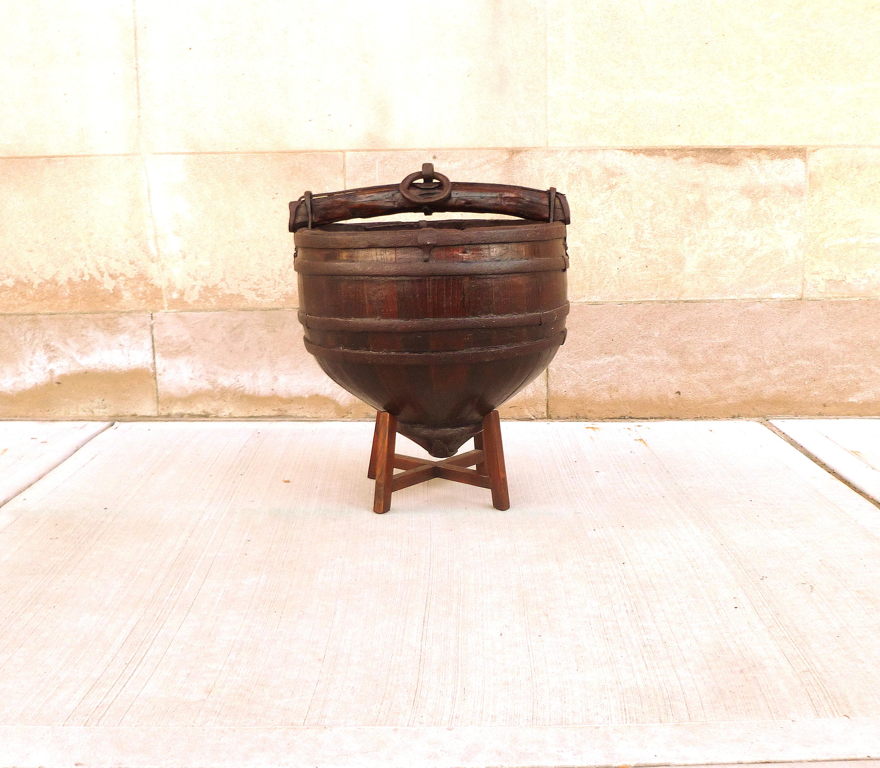 Asian well's water wooden water bucket with handle surrounded with cast iron brackets. We carry fine quality furniture with elegant finished and has been appeared many times in 