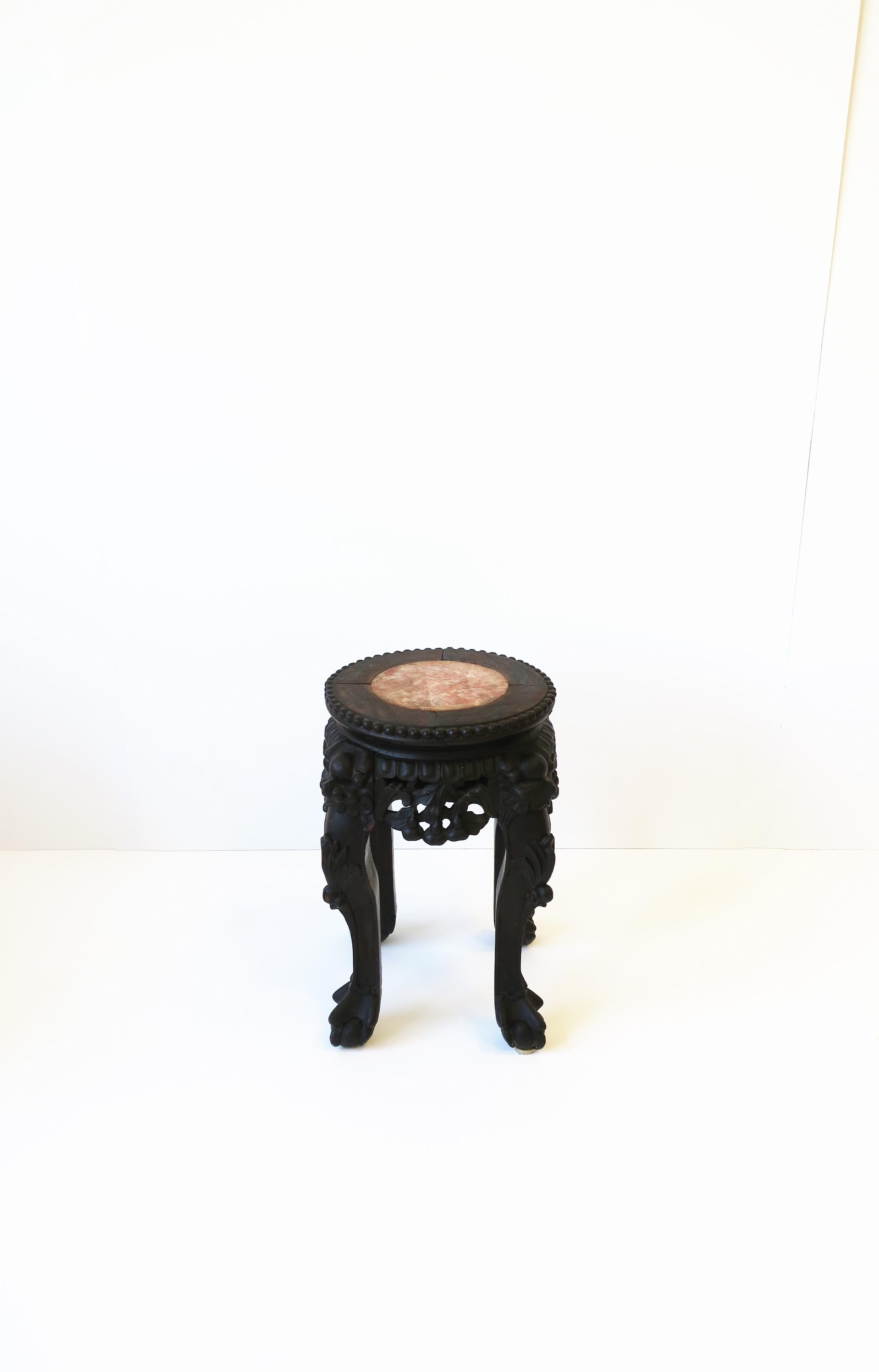 A Chinese carved hardwood table or stand with a rose marble top, circa late-19th century to early-20th century, China. Piece is a rich dark brown carved hardwood with ball and claw feet and a rose marble top. A great piece to hold a cocktail, a