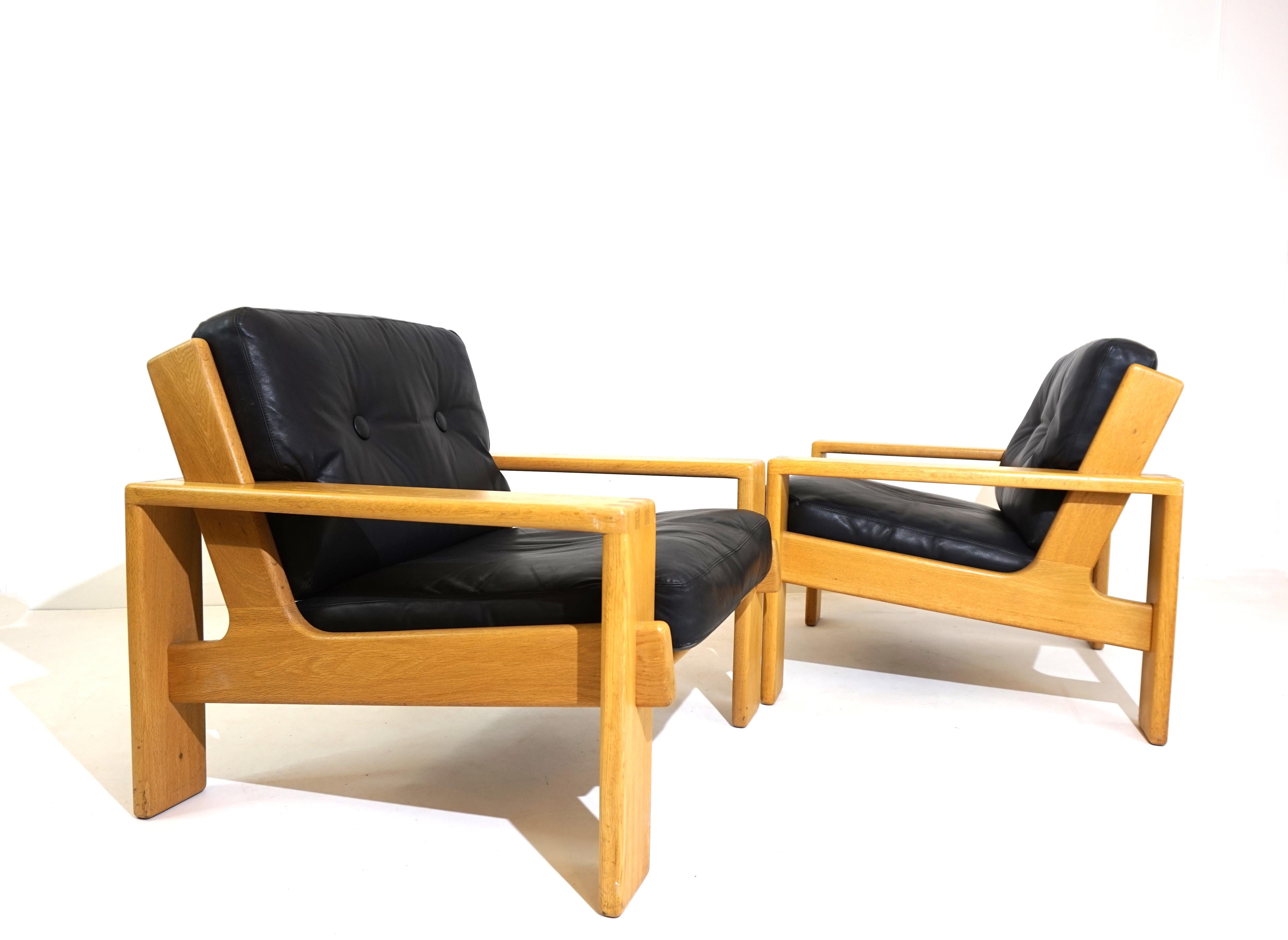 Deux fauteuils Bonanza des années 60 dans une belle combinaison de cuir noir et de cadre en bois clair. Les fauteuils présentent des signes minimes d'usure du cuir, le cuir épais est doux et souple. Les cadres en bois sont en parfait état. Les