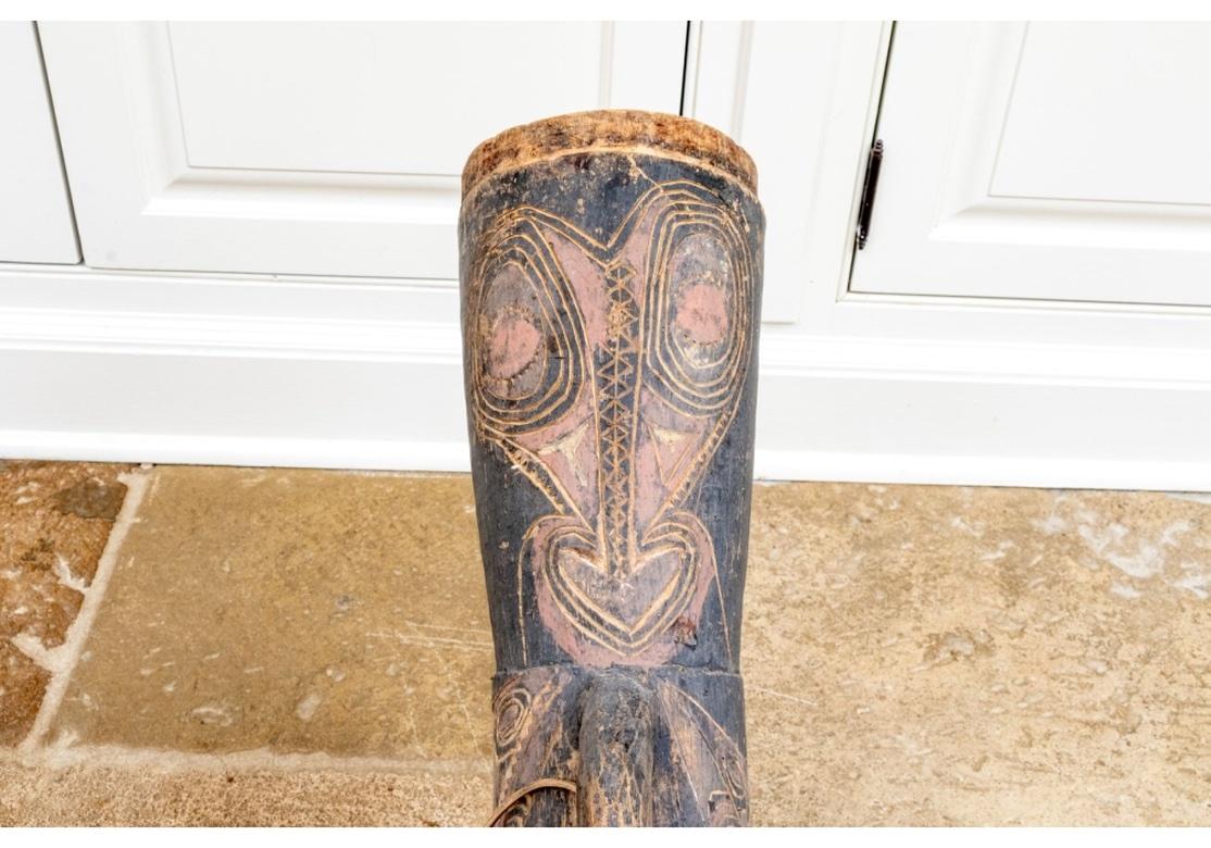 Danza escultórica  Tambor tallado a mano  por la Tribu Asmat Papúa, Nueva Guinea. Tambor fino en forma de reloj de arena con asa en un lado y reborde en el otro, con diseños tradicionales incisos de Máscara y pintado con pinturas minerales y