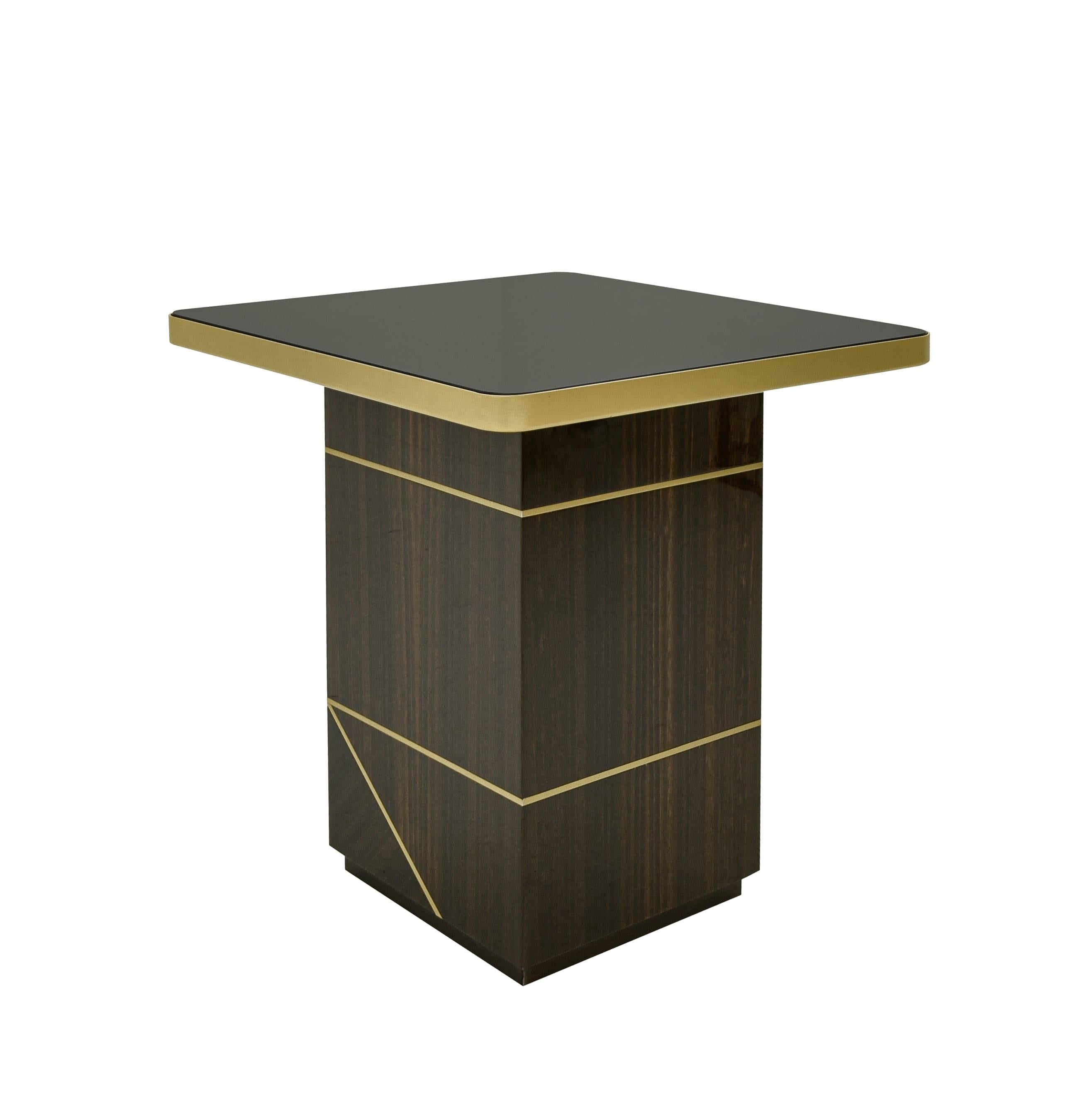 Étude d'équilibre et de contraste des matériaux, cette table d'appoint allie la chaleur du noyer à l'élégance subtile du laiton brossé. Sa conception est définie par  un plateau carré en bois de noyer, tandis que les détails en laiton à la base et