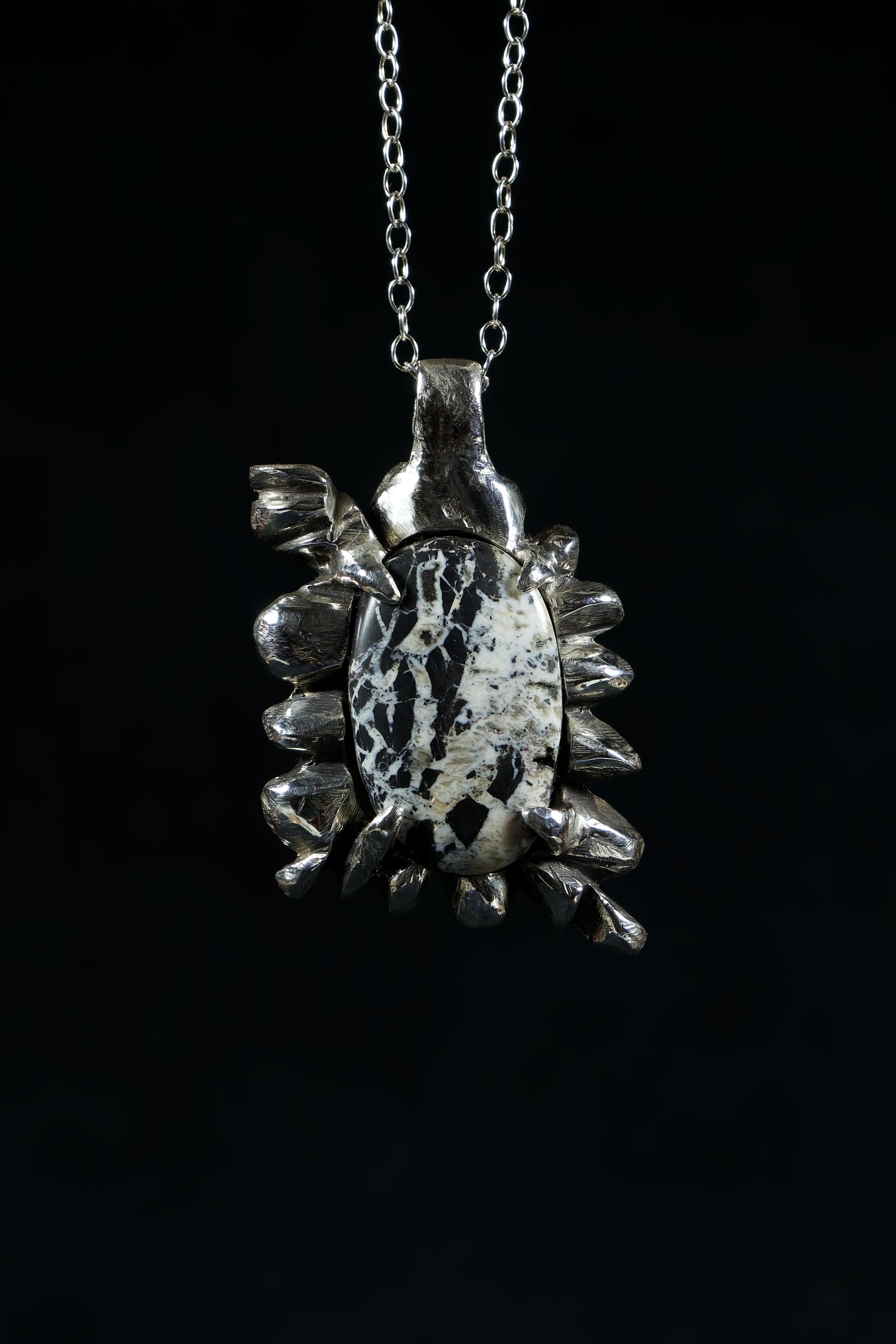 Aspen Tree is an exquisite pendant handcrafted by Ken Fury in sterling silver, featuring a rare and unique White Buffalo Turquoise stone from Nevada. The stone's characteristic white color with black and brown veins resembles the appearance of a