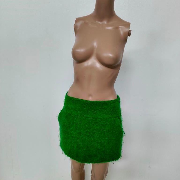Aspesi firma questa mini-gonna scultorea in bouclé verde smeraldo, un pezzo raro che dona un tocco di colore acceso e una texture materica a qualsiasi guardaroba.
Realizzata in un misto lana bouclé con probabile percentuale di mohair, è morbida ma