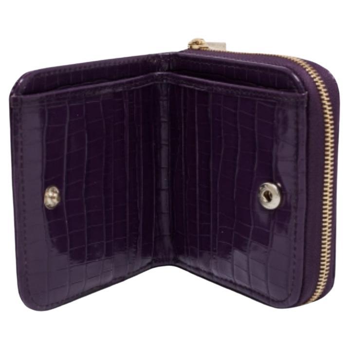 Magnifiquement cousu en cuir verni gaufré au crocodile, ce portefeuille Aspinal of London est résistant et durable. Luxueux et compact, ce portefeuille est doté d'un intérieur bien garni et de ferrures dorées. Il accompagnera certainement vos
