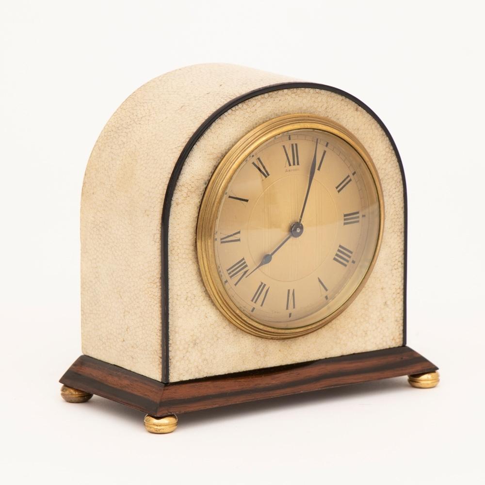 An Asprey Art Deco clock in cream shagreen with black edging on a polished rosewood base and a Swiss movement by Buren c.1920.