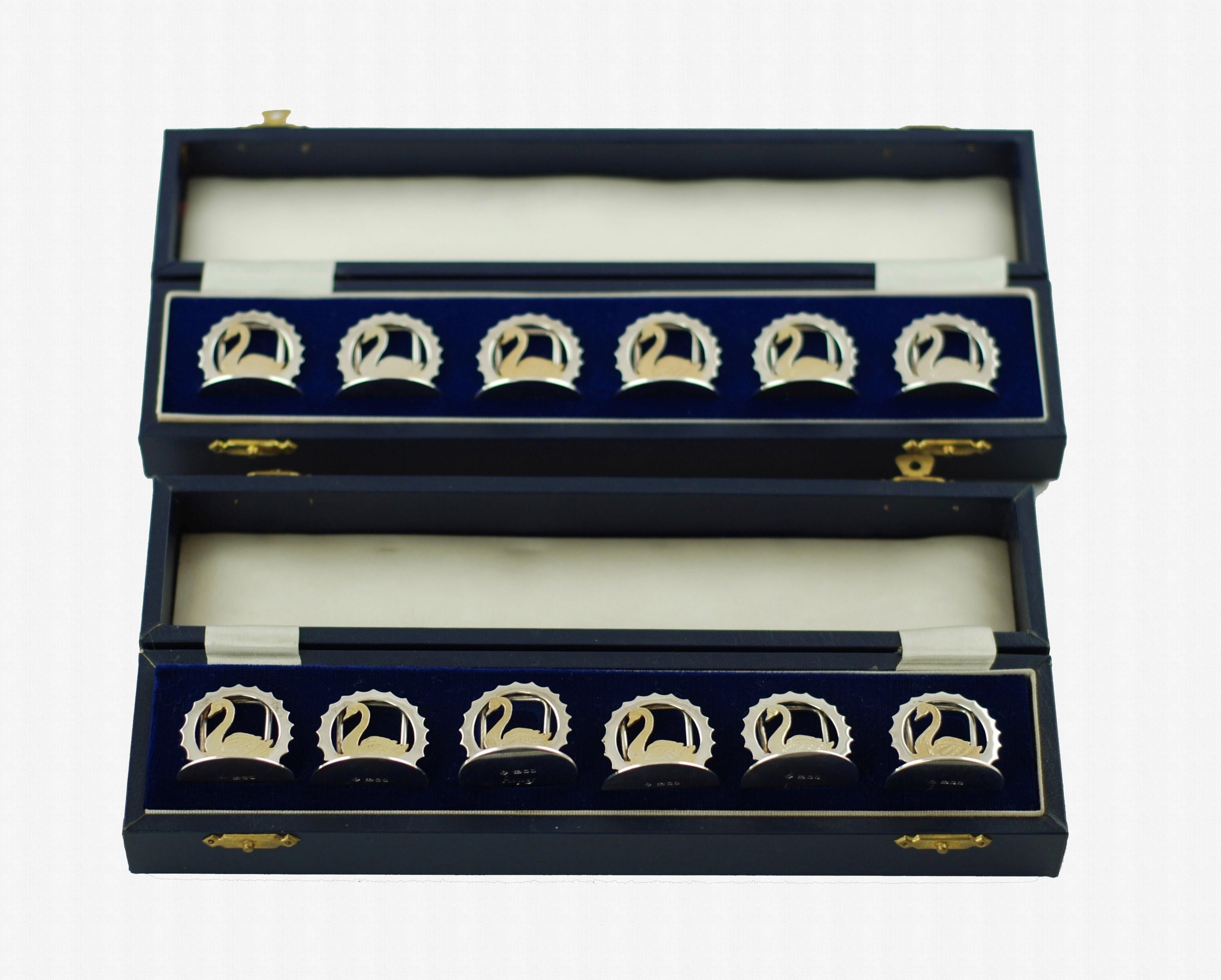 This elegant set of 12 sterling silver menu place card holders was made by Asprey of London. The pieces have circular bases surmounted with arched menu place card supports and feature swans in profile which have been accented in vermeil. The swans