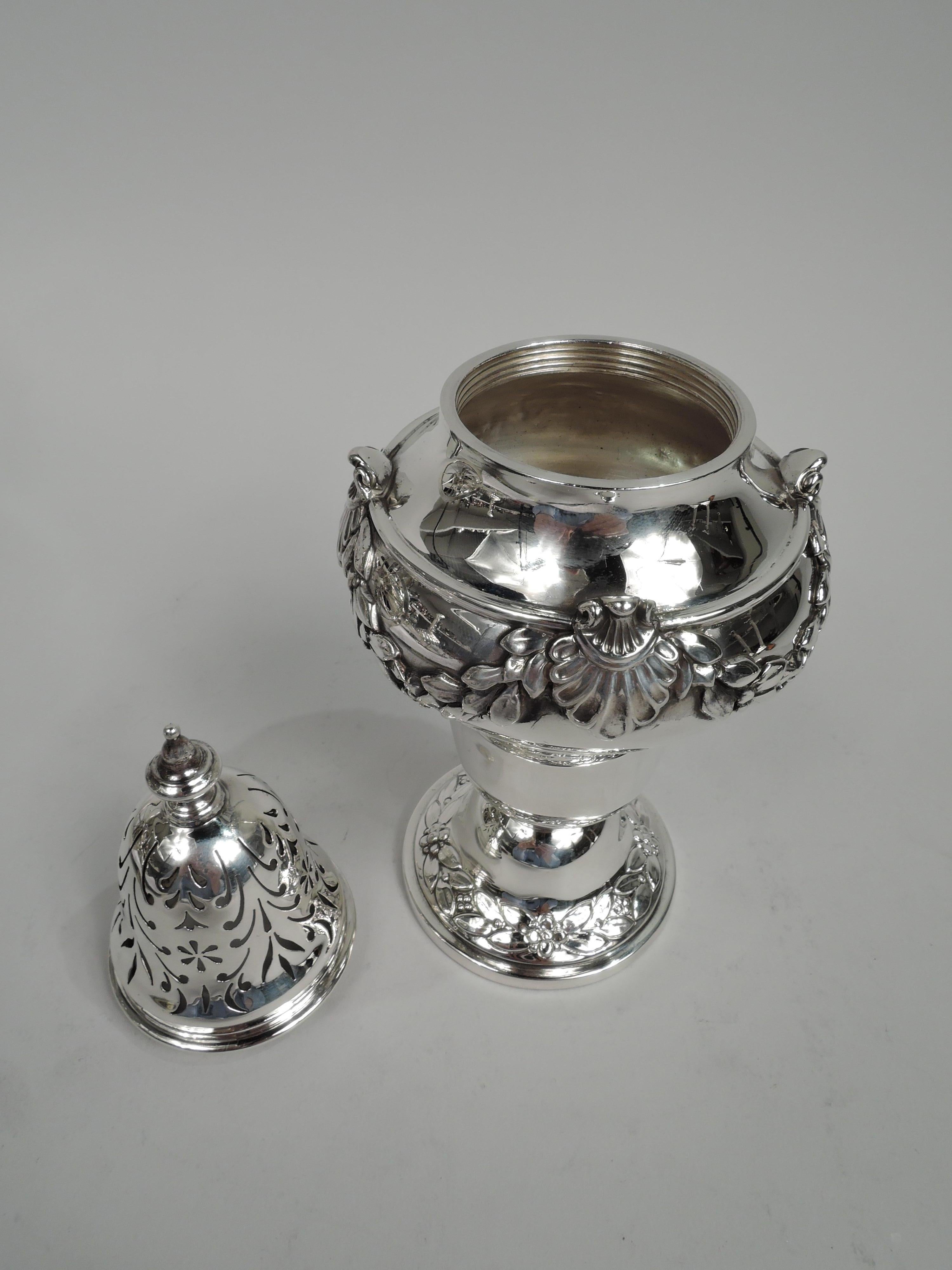 George V sterling silver sugar caster. Made by Asprey & Co. in London in 1911. Baluster with applied shell-mounted garland. Foot domed with chased leaf and flower border. Cover threaded and domed with ornamental piercing and vasiform finial. Pretty