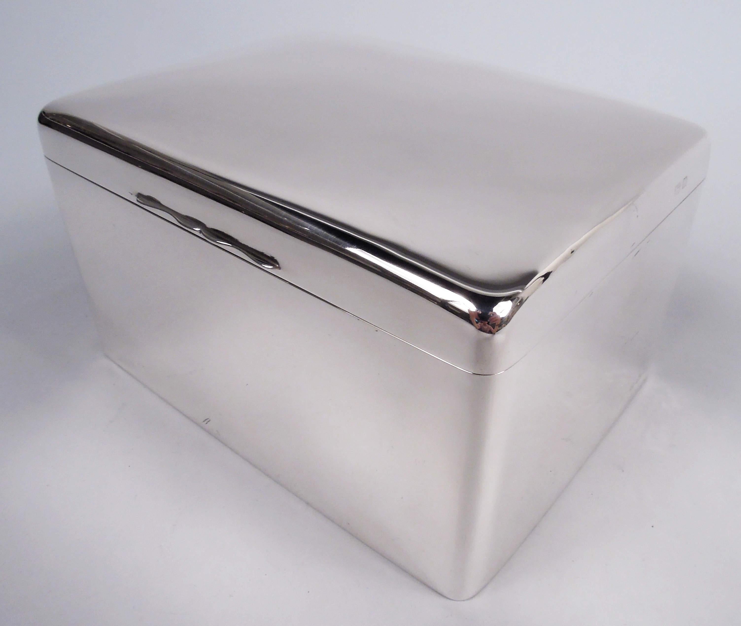 George V sterling silver box. Made by Asprey in Birmingham in 1928. Rectangular with curved corners. Cover hinged with gently curved top and scrolled tab. Box interior cedar lined. Cover interior gilt-washed. Leather-lined underside. Fully marked.