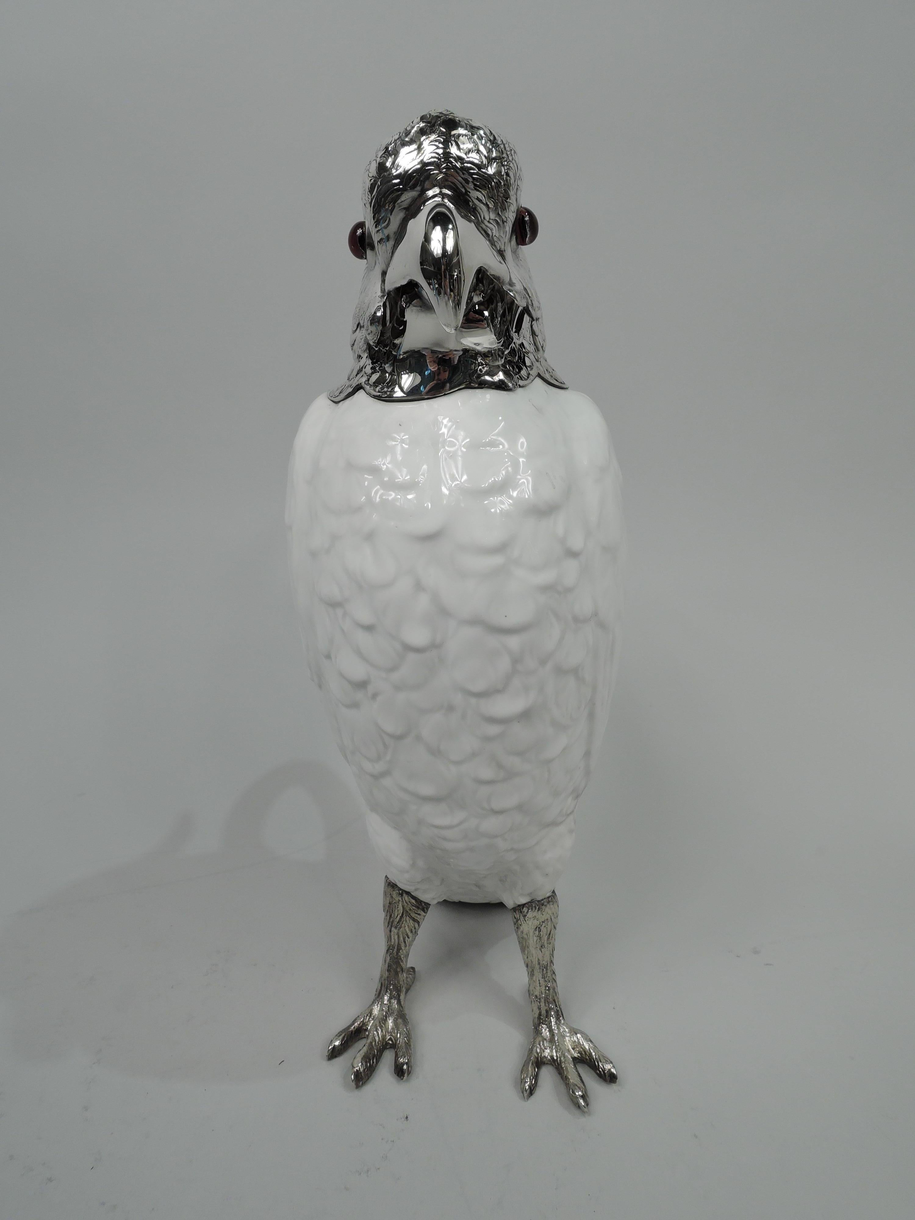 English figural cockatoo decanter, 1913. Blanc de chine body with softly delineated plumage and plain c-scroll handle. Sterling silver stocky legs with scaley talons as well as head with dramatic crown, funny, saggy jowls, and red glass eyes; hinged