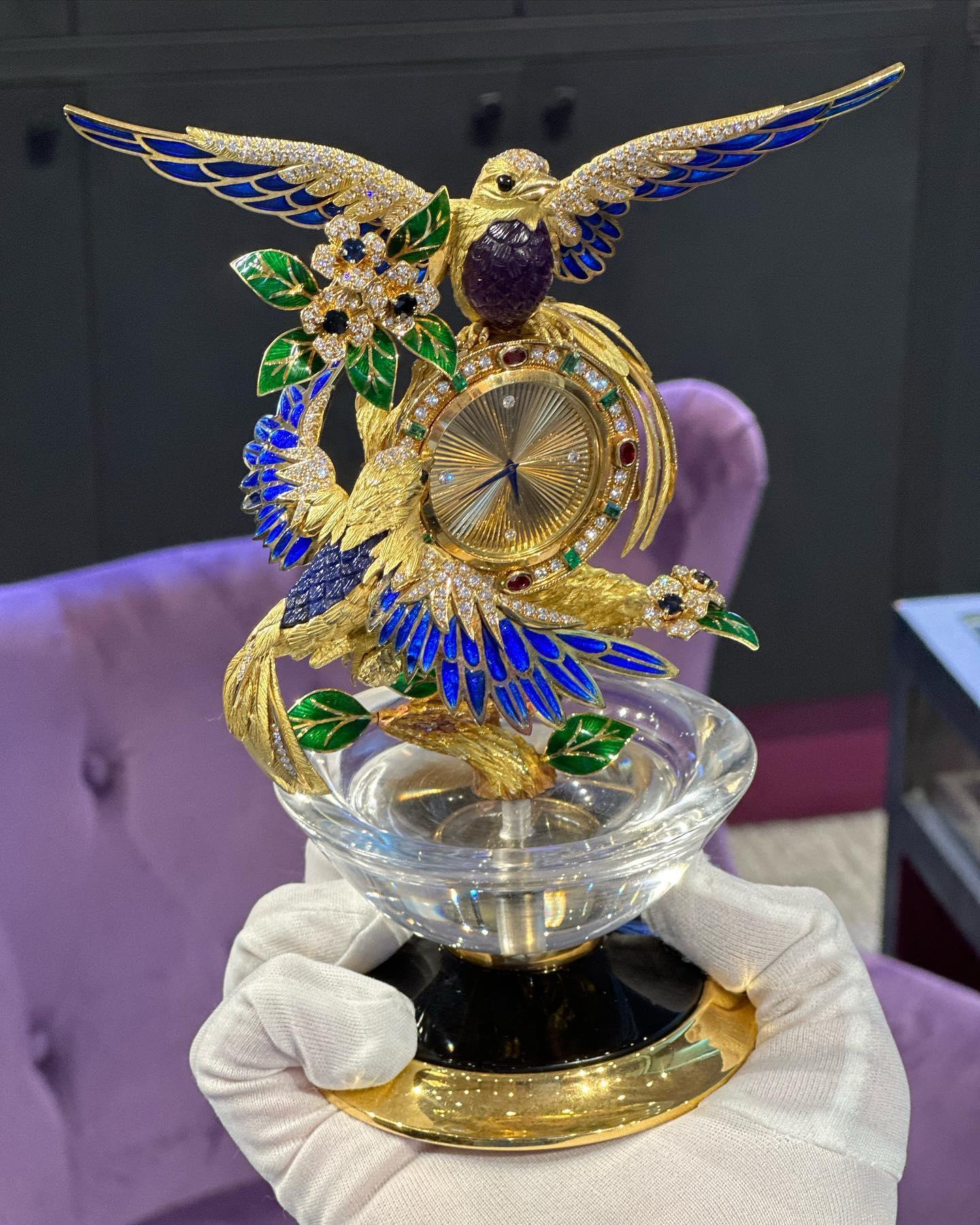  Asprey Gem Set Gold Vogel Uhr

Eine goldene Uhr zwischen zwei Vögeln auf einem Ast, atemberaubend verziert mit Diamanten, Rubinen, Smaragden, Saphiren, Amethysten und blauer und grüner Emaille. Der Sockel besteht aus Bergkristall auf Onyx und