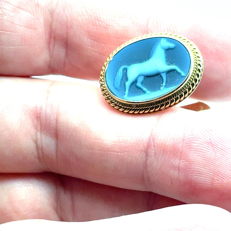 Distinctive and attractive cufflinks.  Made and signed by ASPREY.  Blue ceramic portrait plaques, depicting three-dimensional prancing white horses.  The cufflinks are left and right; the horses face each other.  Set in a solid gauge 18K yellow gold