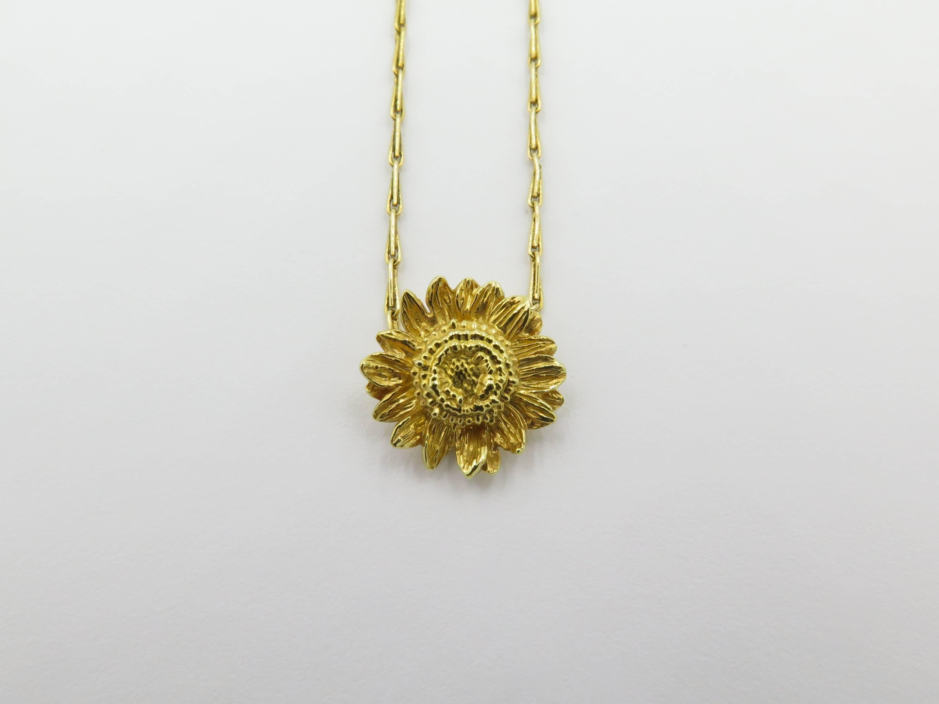 An 18 karat yellow gold necklace. Asprey. From the Sunflower collection. Designed as a fancy link chain, centering a textured gold sunflower, Diameter of sunflower is approximately 1/2 inch, length of chain is approximately 16 inches. Gross weight