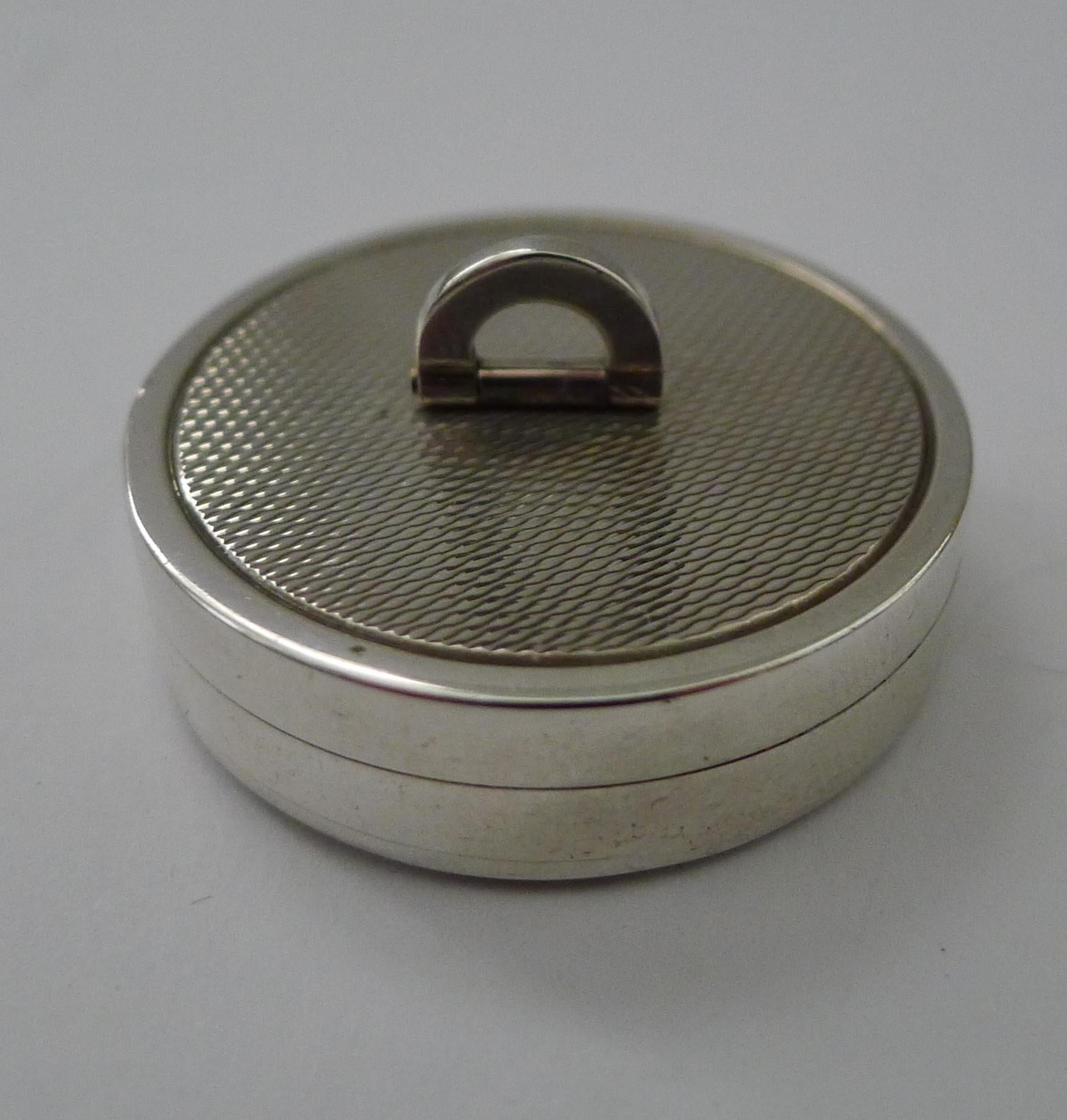A fabulous late Art Deco style pill box, beautifully made with a folding campaign style handle which folds flat.

The box is decorated both on the lid and the underside with engine turning.  The lid fits well and once the lid is removed reveals an
