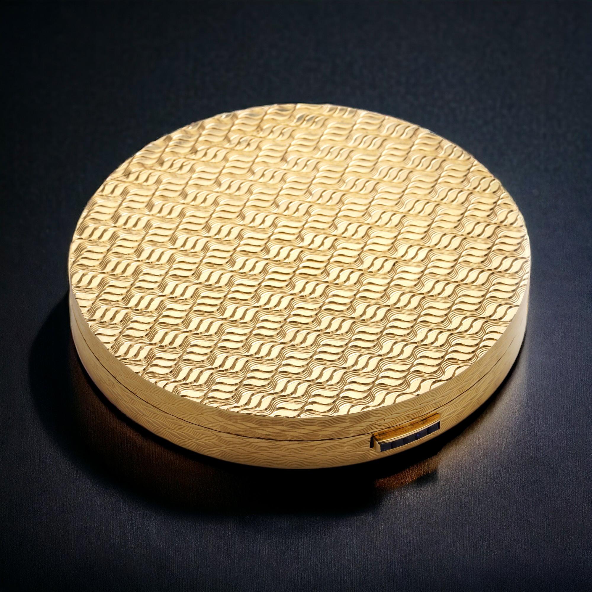 Experience the timeless allure of Asprey vintage 18kt gold compact case, adorned with a delicately crafted mirror for your convenience. Five exquisite calibre cut blue sapphires grace the button, enhancing its charm. Crafted in the heart of London,