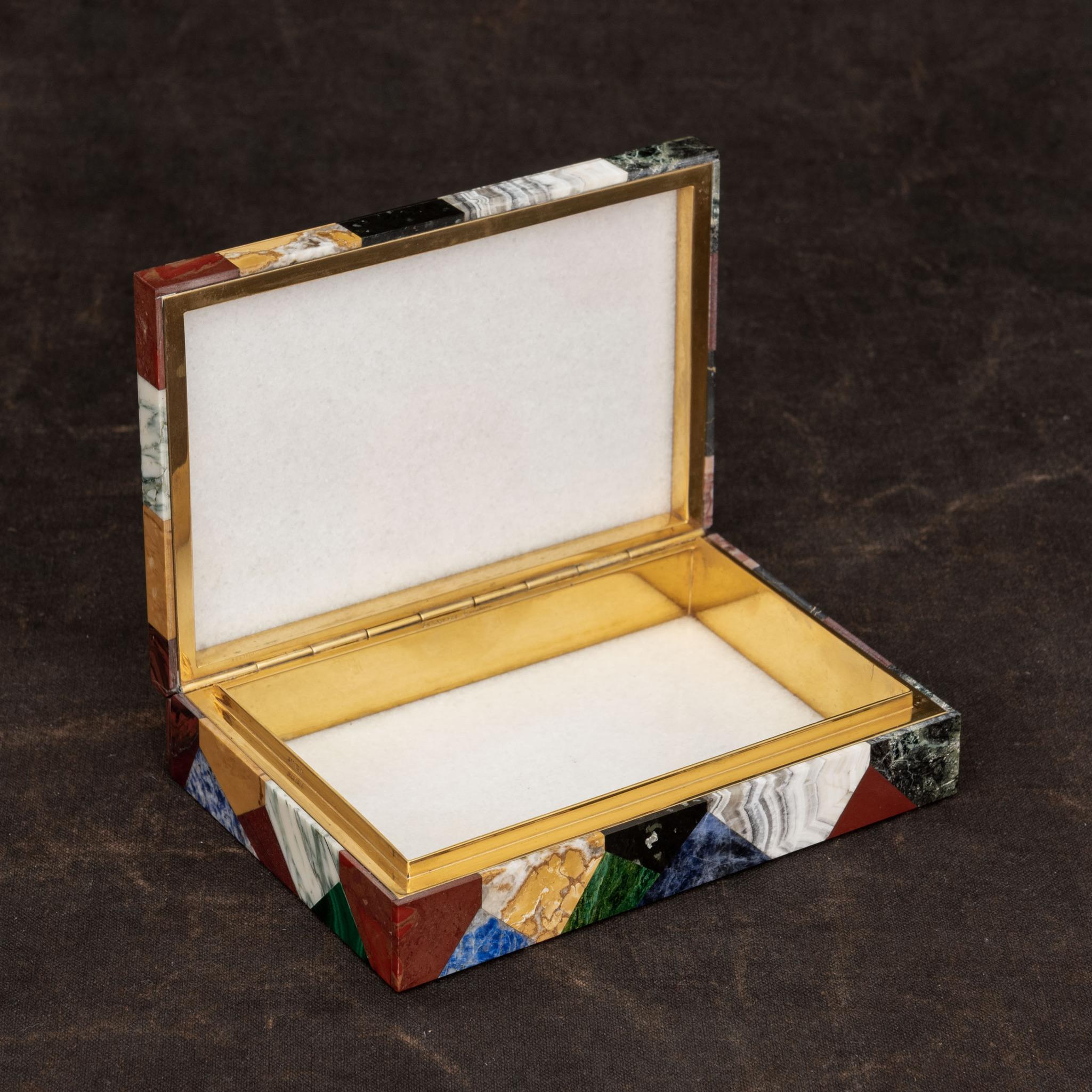 Unusual stone box displaying a patchwork of multiple semi-precious stones with a white agate interior. Originally used as a cigarette box, a gilt metal hinge that joins the top and bottom sections is marked Asprey London. Circa 1940.

Dimensions: