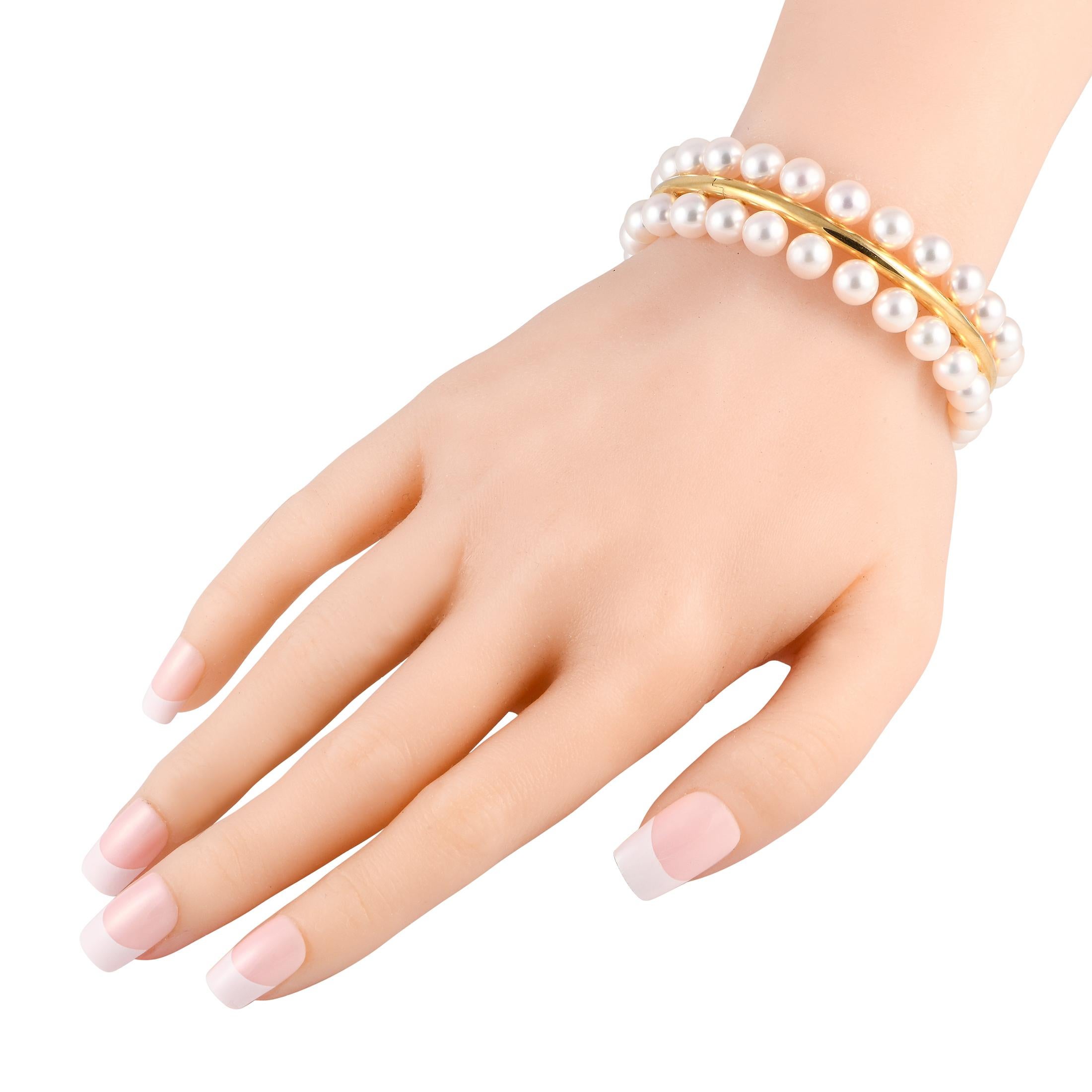 Embrace your classic sensibilities with this yellow gold and pearl bangle bracelet from the House of Assael. It features a polished, rigid bracelet adorned with two circular rows of Akoya cultured pearls, each measuring approximately 7.5mm to