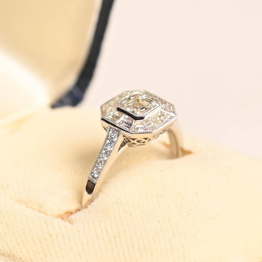 Cette exquise bague de fiançailles Diamond Halo met en valeur un remarquable diamant Asscher d'environ 0,50 carat, serti en chaton pour un look élégant et sophistiqué. Certifiée par le Gemological Institute of America (GIA), la pierre centrale