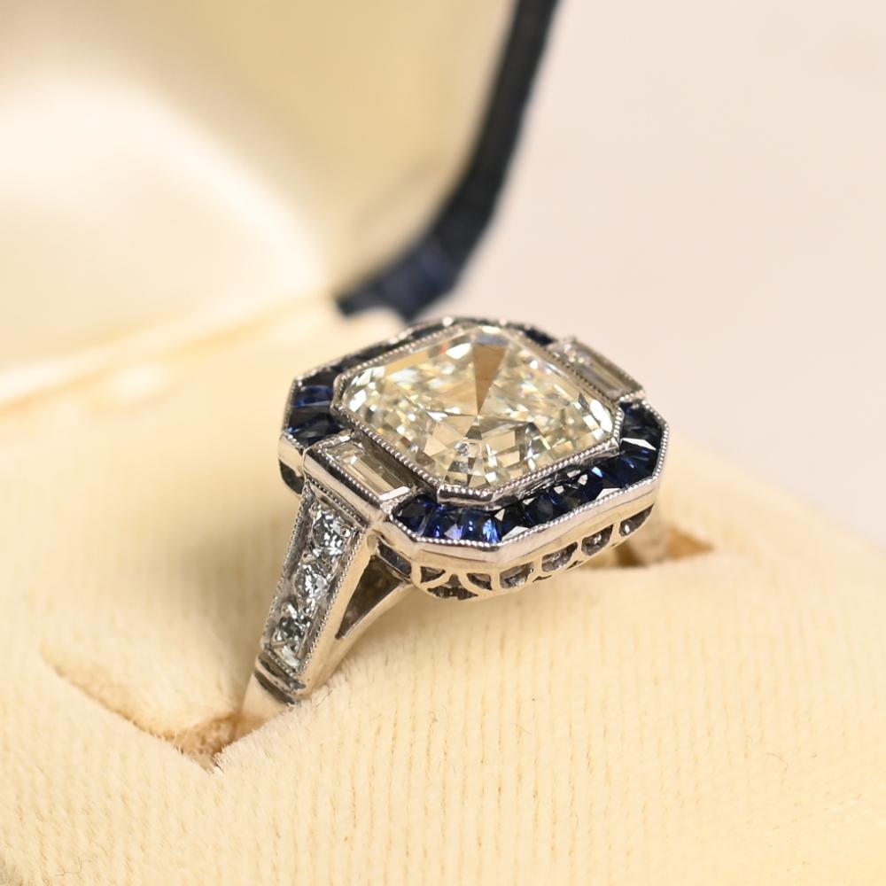 Este llamativo anillo geométrico se centra en un magnífico diamante talla Asscher GIA de aproximadamente 3,00 quilates, graduado en color K con una excepcional claridad VVS1. Las distintivas facetas escalonadas de la talla Asscher crean un