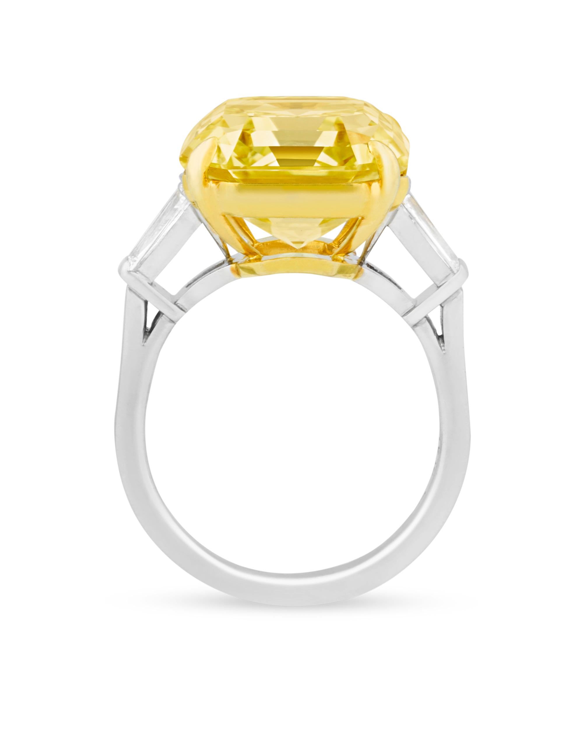 An Asscher-cut 12.33-carat fancy intense yellow diamond displays its radiant hue in this incredible ring. The rare stone is certified by the Gemological Institute of America to be natural fancy intense, a grade that is the most desirable in diamonds
