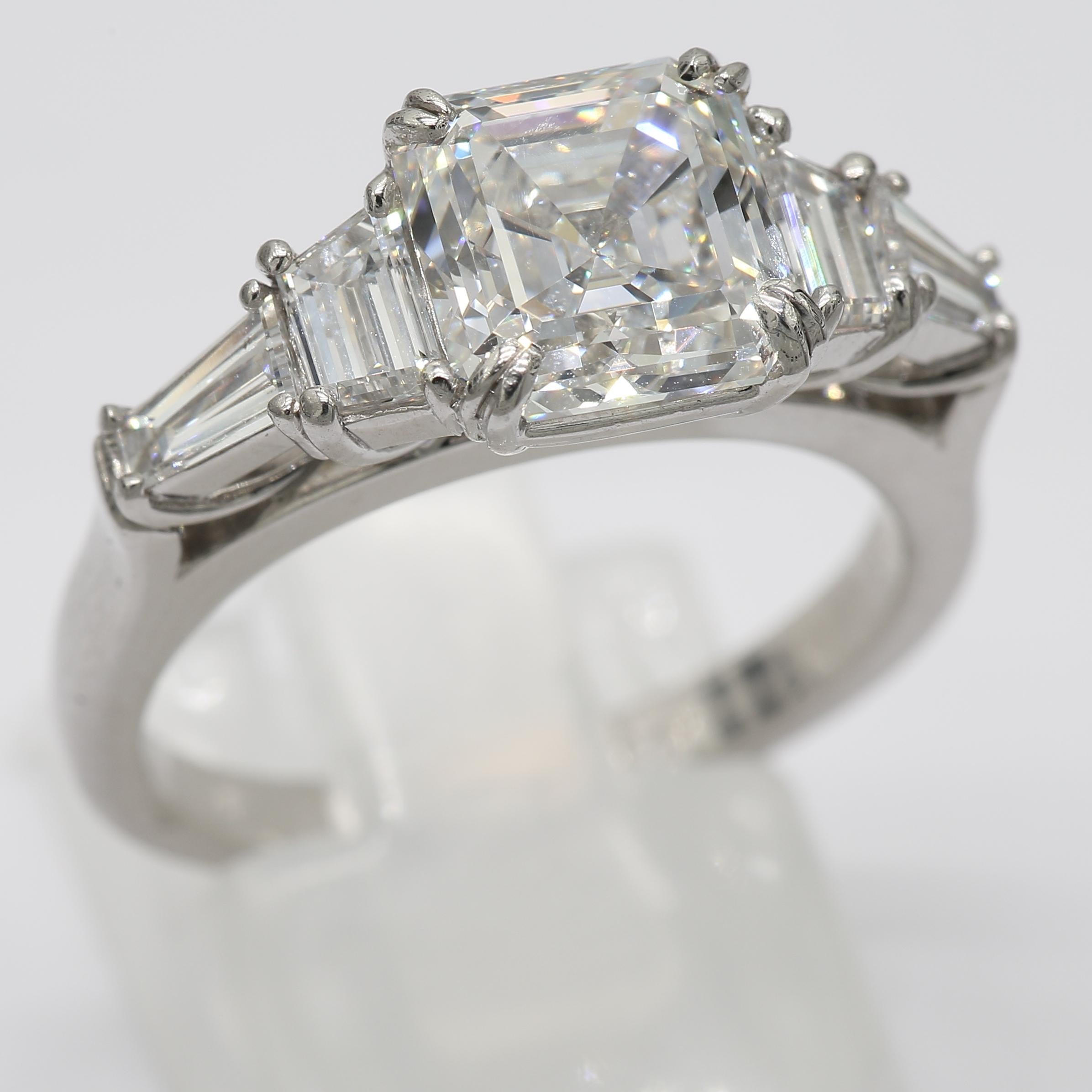 An Asscher Diamond of 3.06 Carat set next to four Baguette/Trapez Cut Diamonds of 1.2 Carat to create an impressive ring in Platinum Metal. The beautiful vintage style bridge gives the ring an elegant touch and holds the diamonds high. Dress to