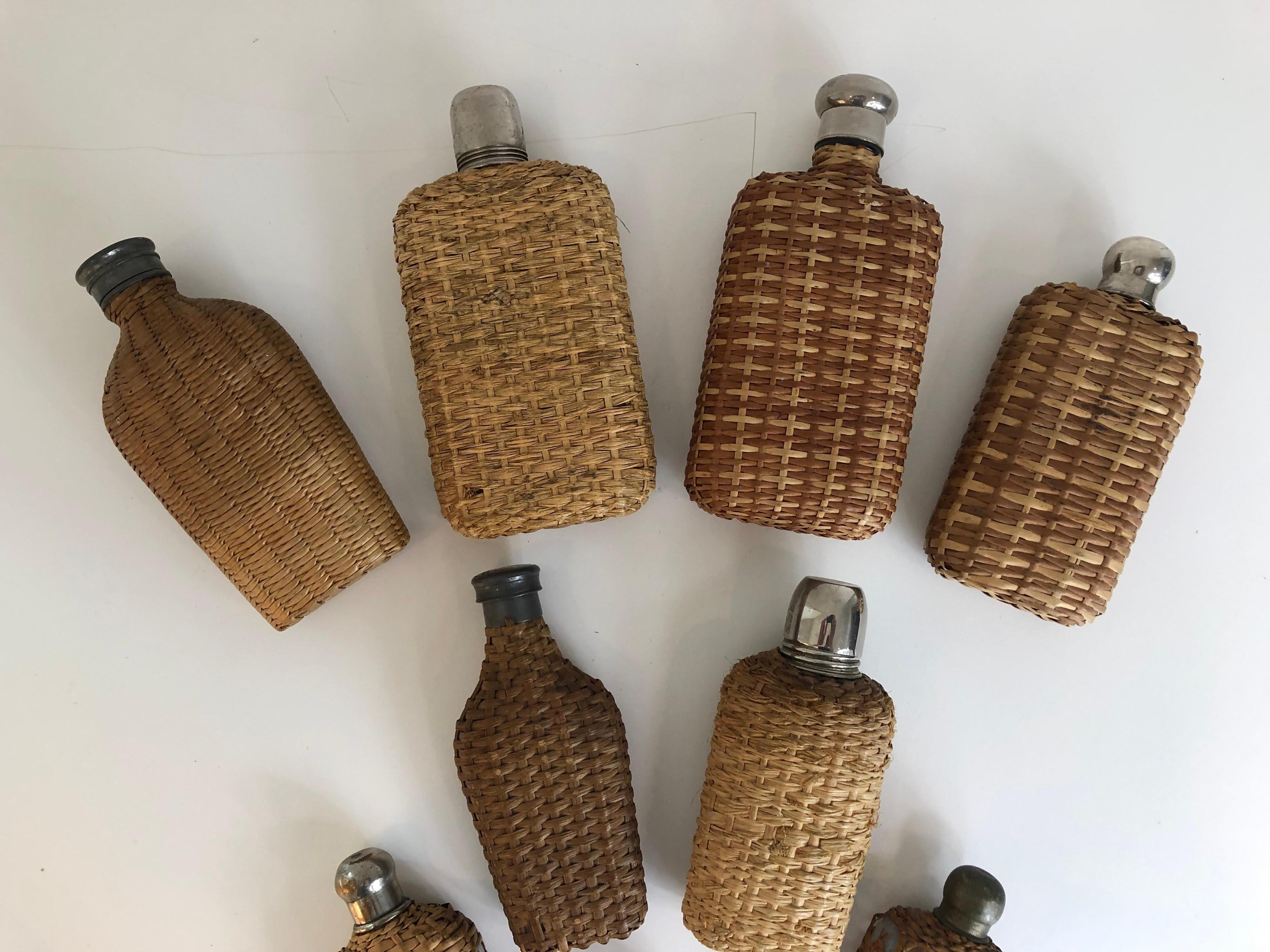 An assembled collection of nine vintage handwoven wicker flasks. Collection includes some wicker over glass, pewter, and silver, early 20th century. Largest measures: 7