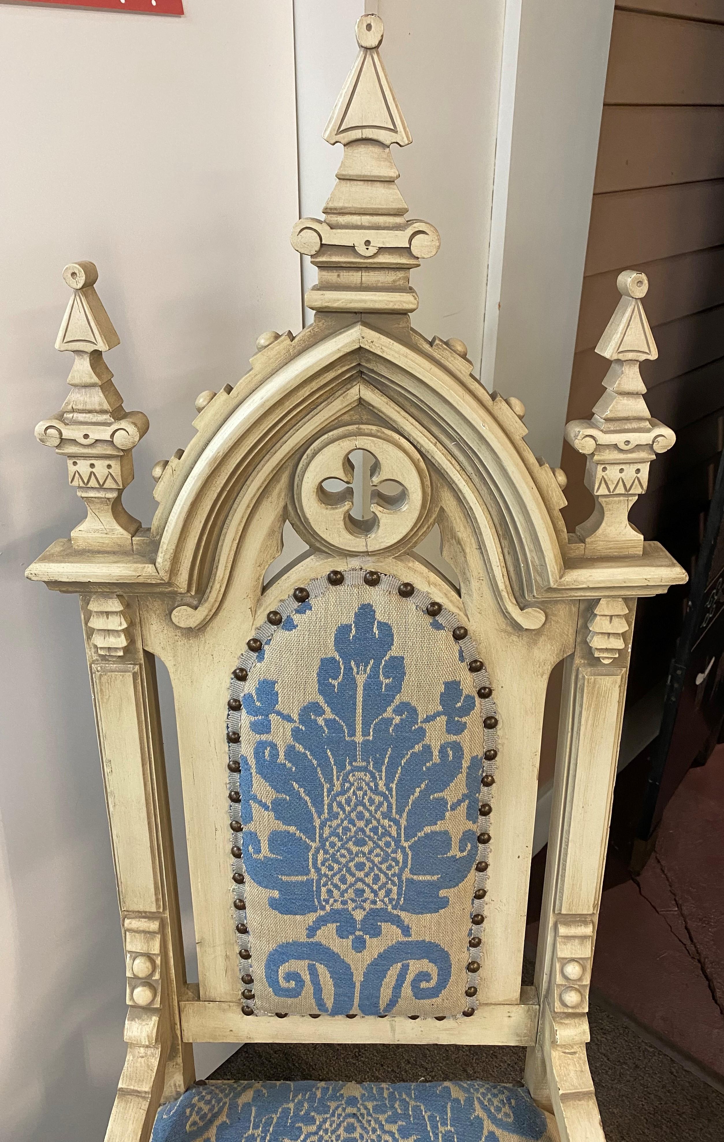 A fine assembled pair of Gothic Revival side chairs, painted in white and upholstered in blue & white. The backs, legs, and crests are ornately carved, one slightly larger than the other, perhaps the man’s chair. The set dates to late 19th or early