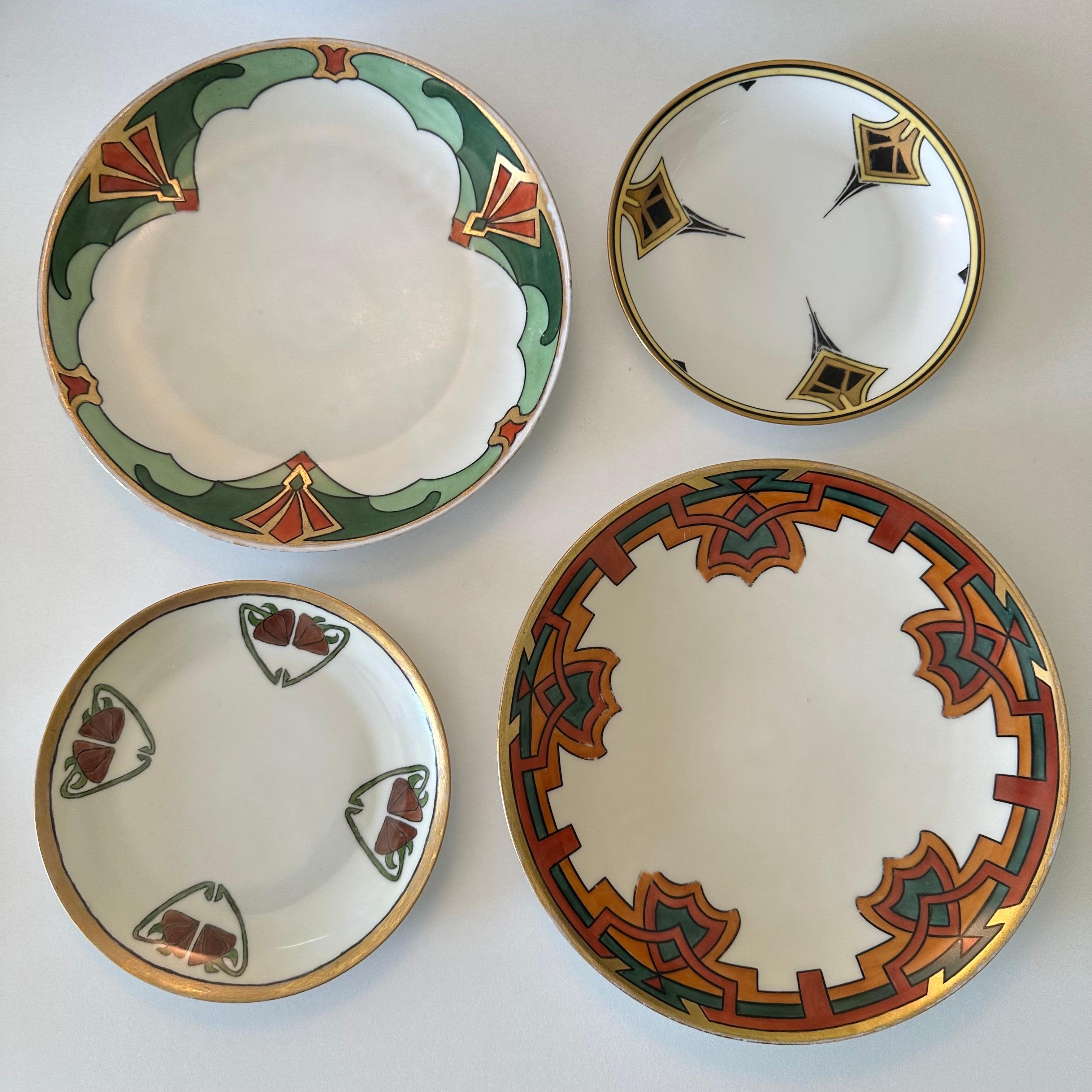 This is a collected set of four unique, hand painted, antique plates of differing sizes by Hutschenreuther, Bavaria and Haviland, France. Pairing together well with complimentary Art Deco and Art Nouveau motifs, gilded details and black outlines are