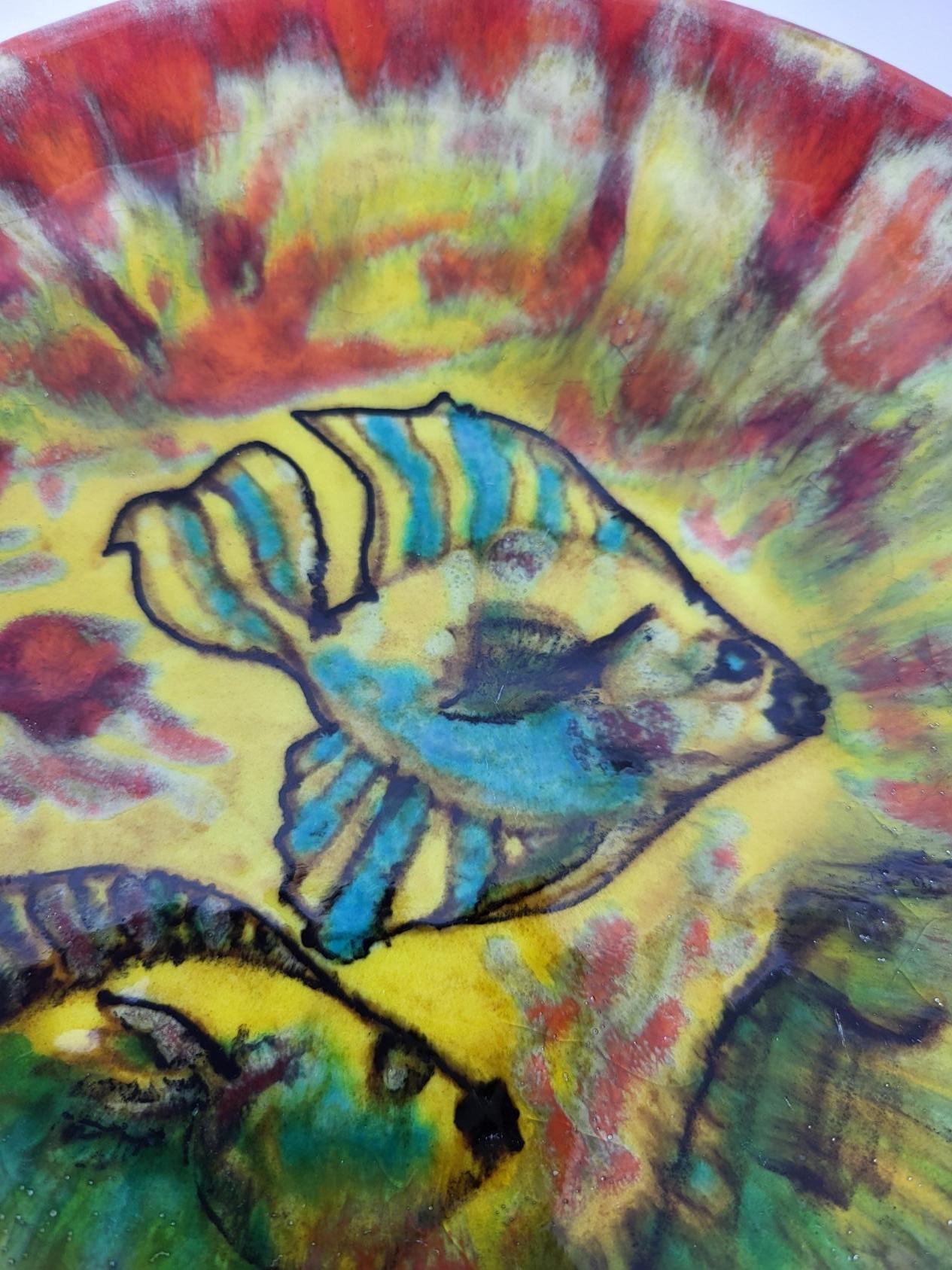 L'assiette en céramique richement décorée de poissons exotiques multicolores est une œuvre emblématique de l'artiste breton Yves-Alain Pleuven, connu sous le nom de Youen. Né en 1929 et décédé en 2015, Pleuven a su capturer l'essence de la mer et de