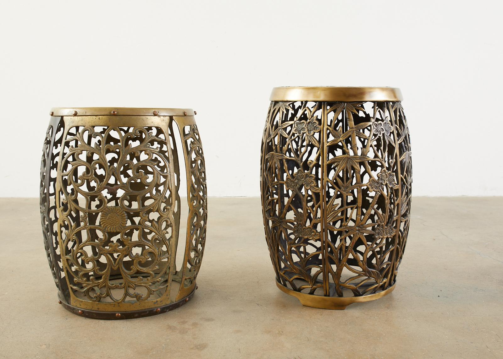 Associated pair of Chinese pierced brass drum garden stools or drink's tables. Made in the tabouret style featuring an elaborate open fretwork cage design of bamboo, foliage, and scroll patterns. One stool measures two inches higher than the other