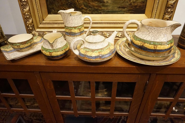Wonderful set of 8 assorted pieces by Royal Doulton in a crackle glaze with landscape motif including kettle, jars, creamer, cup and plates. Intact and beautifully rendered from the Arts and Crafts era. Serial numbers and stamps on all the pieces