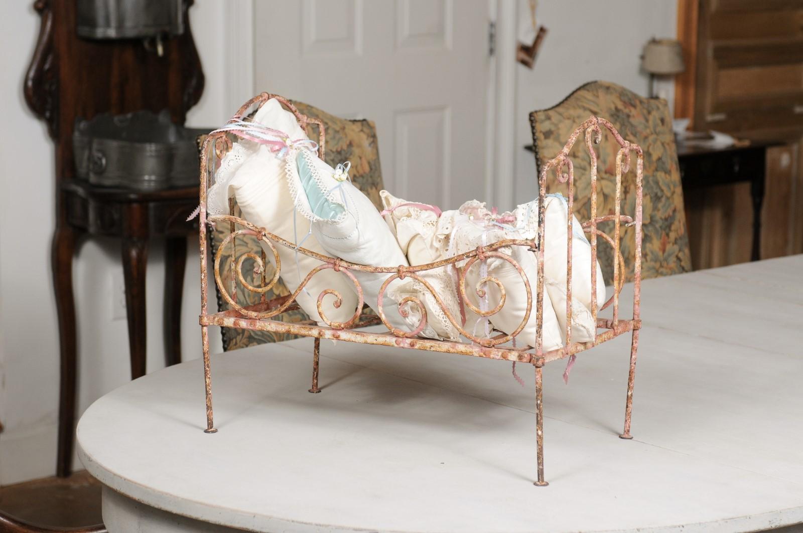 An assortment of vintage French lace pillows in 19th century metal crib. Created in France during the 19th century, this petite crib captures our hearts with its delicate arrangement of vintage lace pillows tied with blue and pink ribbons. Boasting