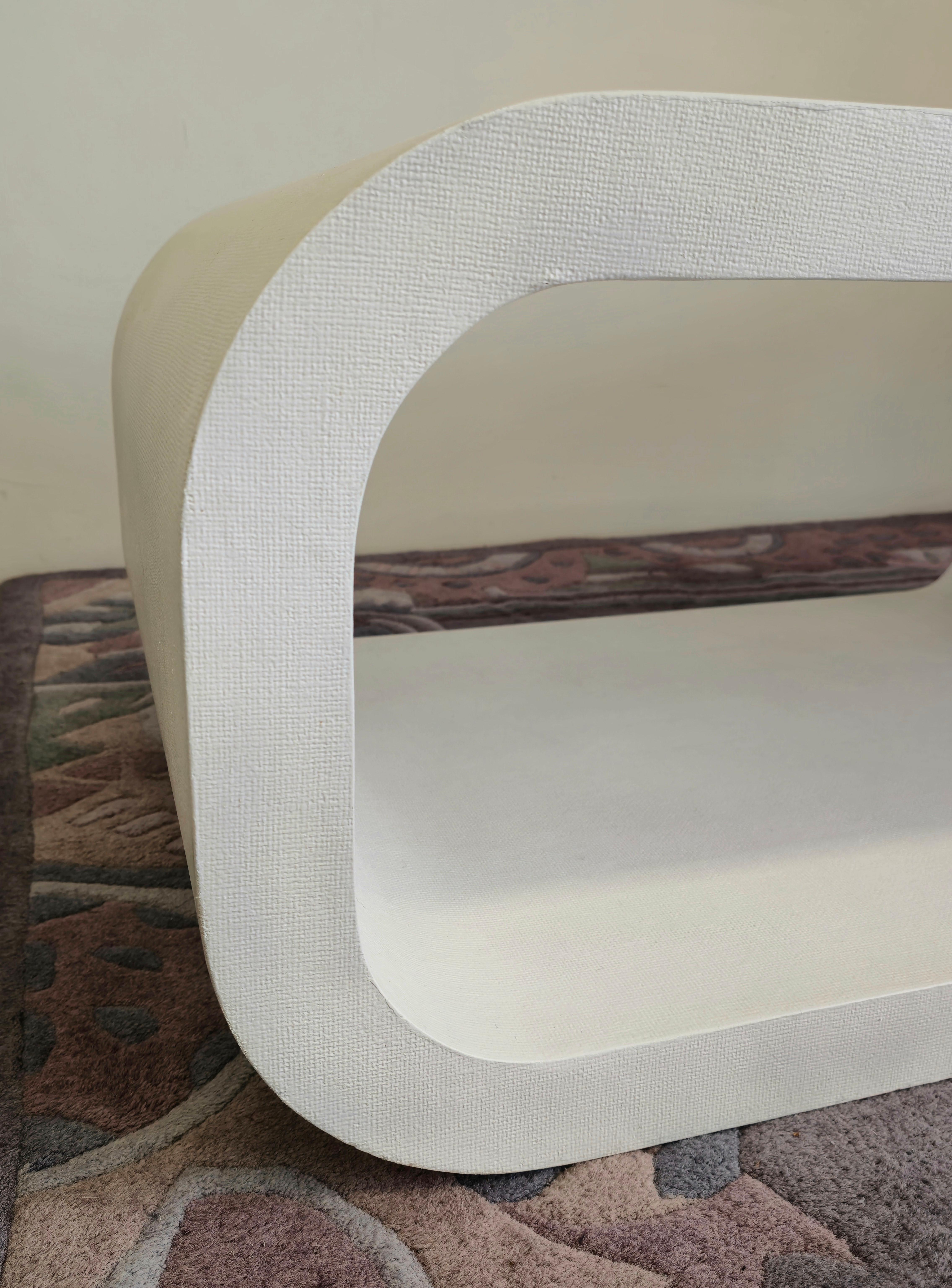 A stunning assymetrical cantilevered coffee table made in the 1970s. This meticulously crafted coffee table is cantilevered and linen wrapped with a white finish. The cantilevered shape has a wider top with a more narrow footing which is curved