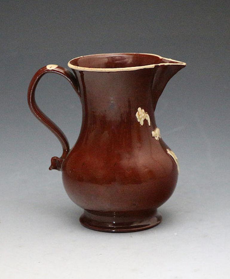 A rare fine lead-glazed redware baluster shaped earthenware pitcher with a loop-shaped handle pinched at the lower terminal. The sparrow beak shaped pouring lip is hand formed and expertly applied. The relief decoration of twigs, flowers and