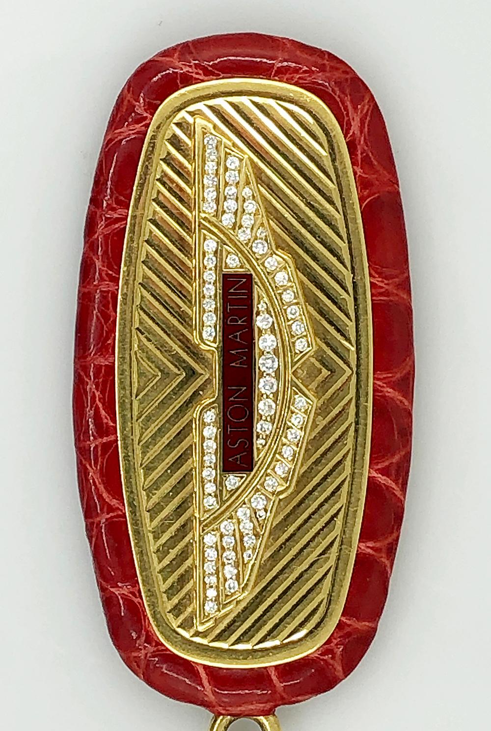 A rare diamond Aston Martin keychain comprised of 18k yellow gold adorned with diamonds and framed with red leather.