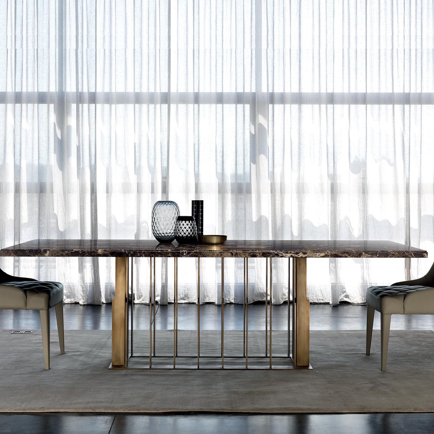 This stunning dining table is defined by clean forms and an elegant aesthetic. The rectangular metal structure, in stainless steel with polished brass finish, is composed of irregularly-edged vertical elements positioned in line with the four outer