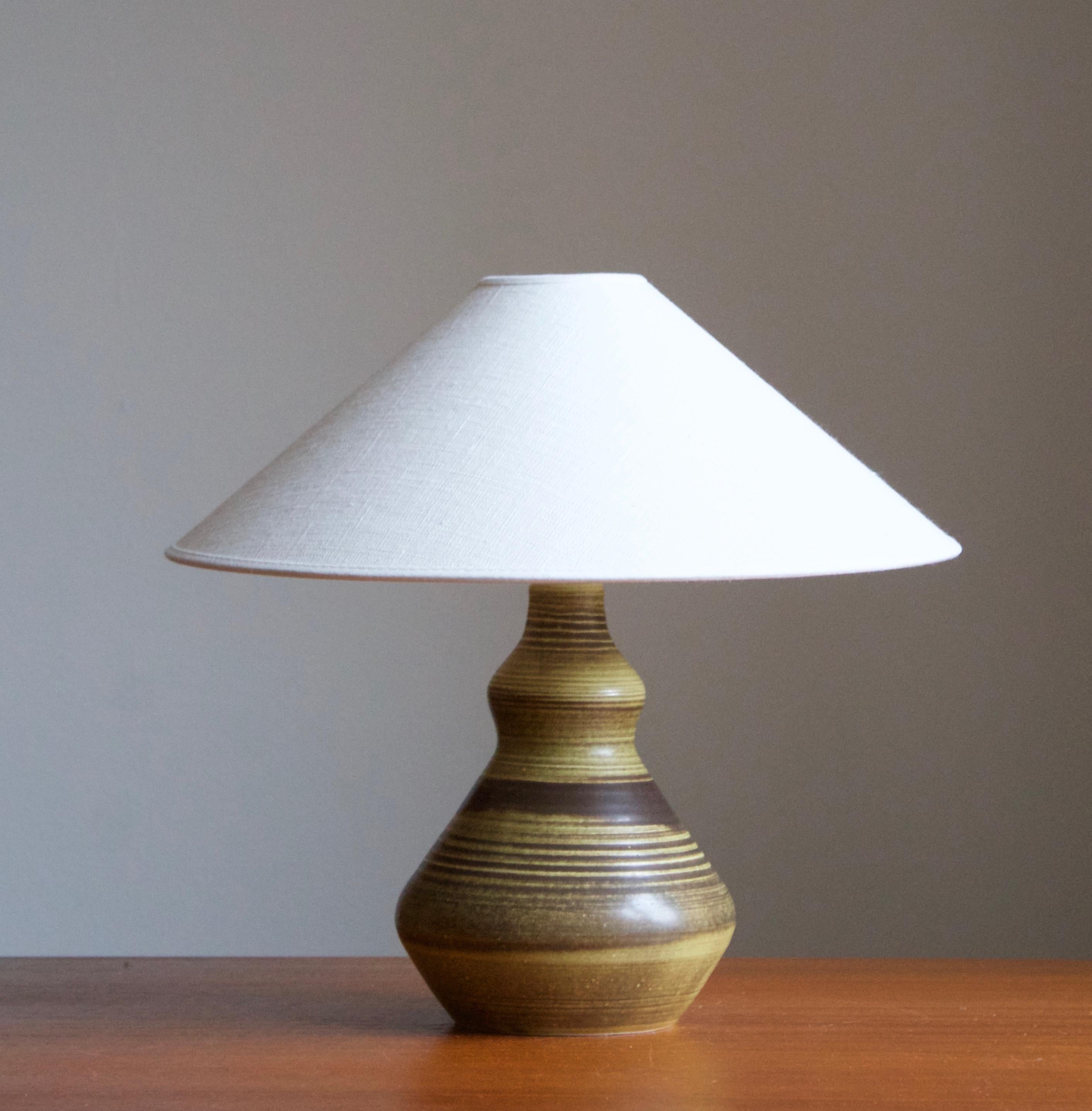 A stoneware table lamp, executed by Astrid Nordgren, Studio, Norway, 1979. Signed at bottom. With an artistic glaze and finely incised decor.

Stated dimensions exclude lampshade. Height including socket. Sold without lampshade.

Glaze features