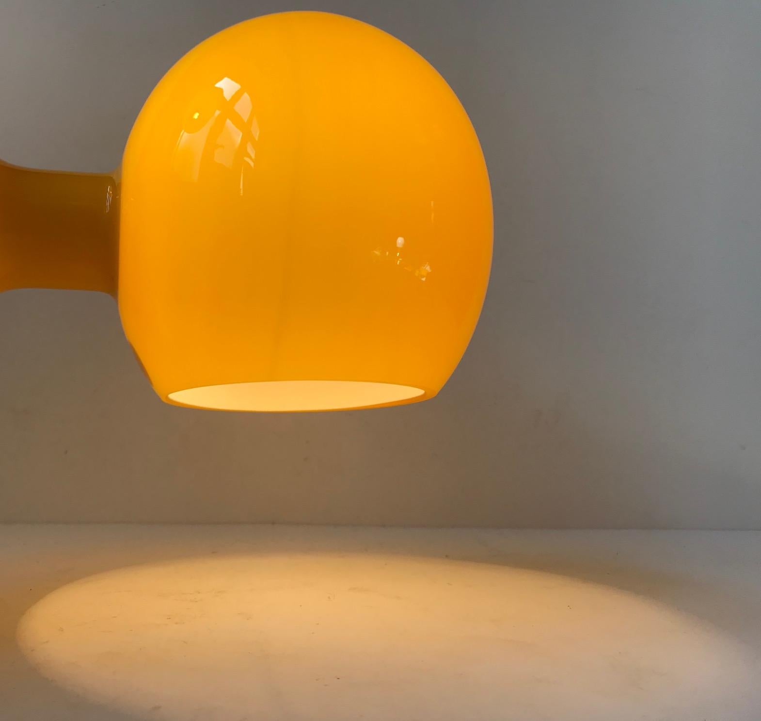 - Bright yellow glass table or wall Lamp, model Astronaut, designed by Michael Bang 
- Manufactured by Holmegaard in Denmark in 1967
- Cased yellow glass exterior and opaline interior
- Light source: E14 / E12 Edison screw fitting, max 40W.