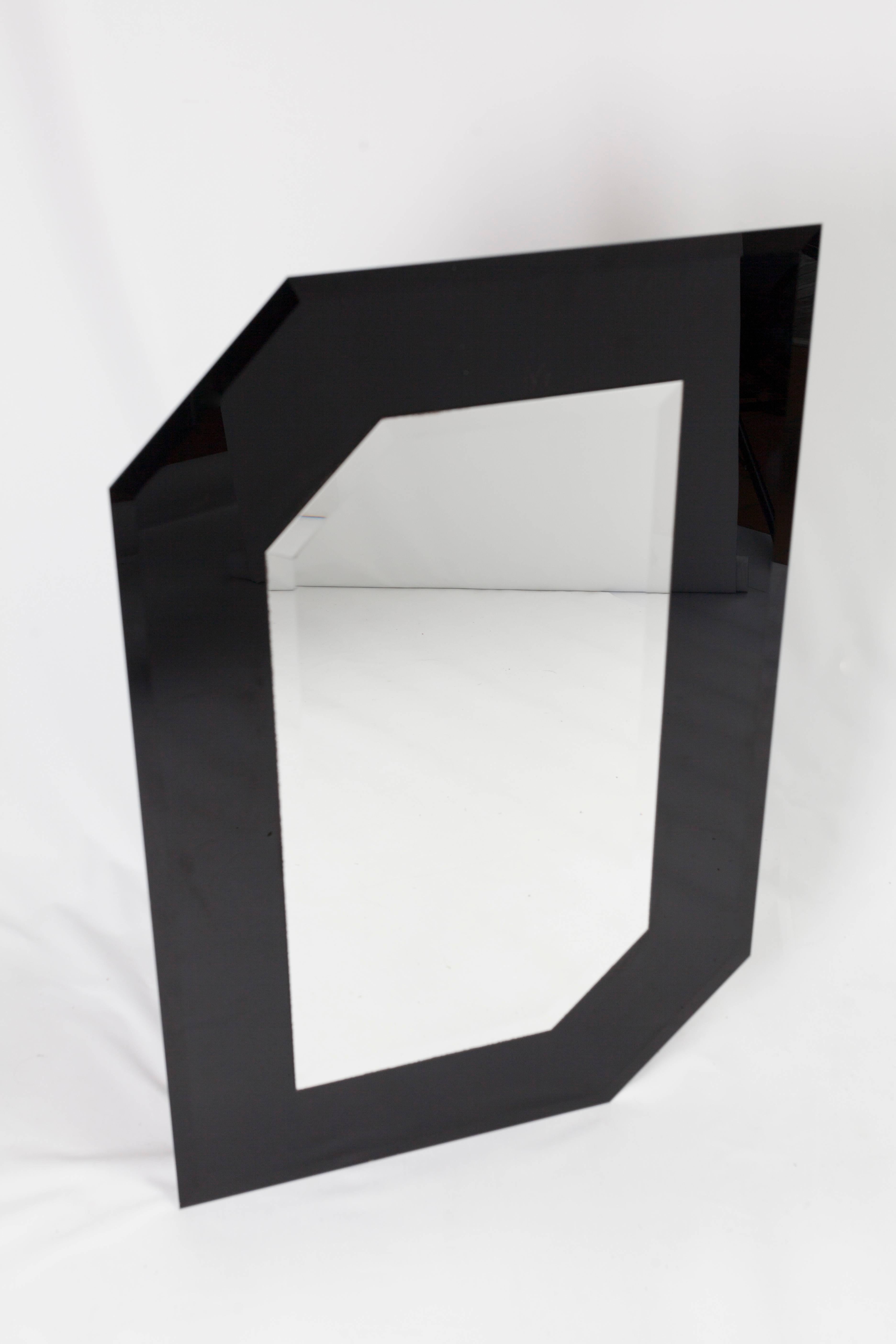 Beautiful asymmetric wall mirror with black glass 'frame' in postmodern style.
This mirror is made of a black glass asymmetric base with a mirror in the same asymmetric shape upon it.
Both the glass and the mirror have cut rims.