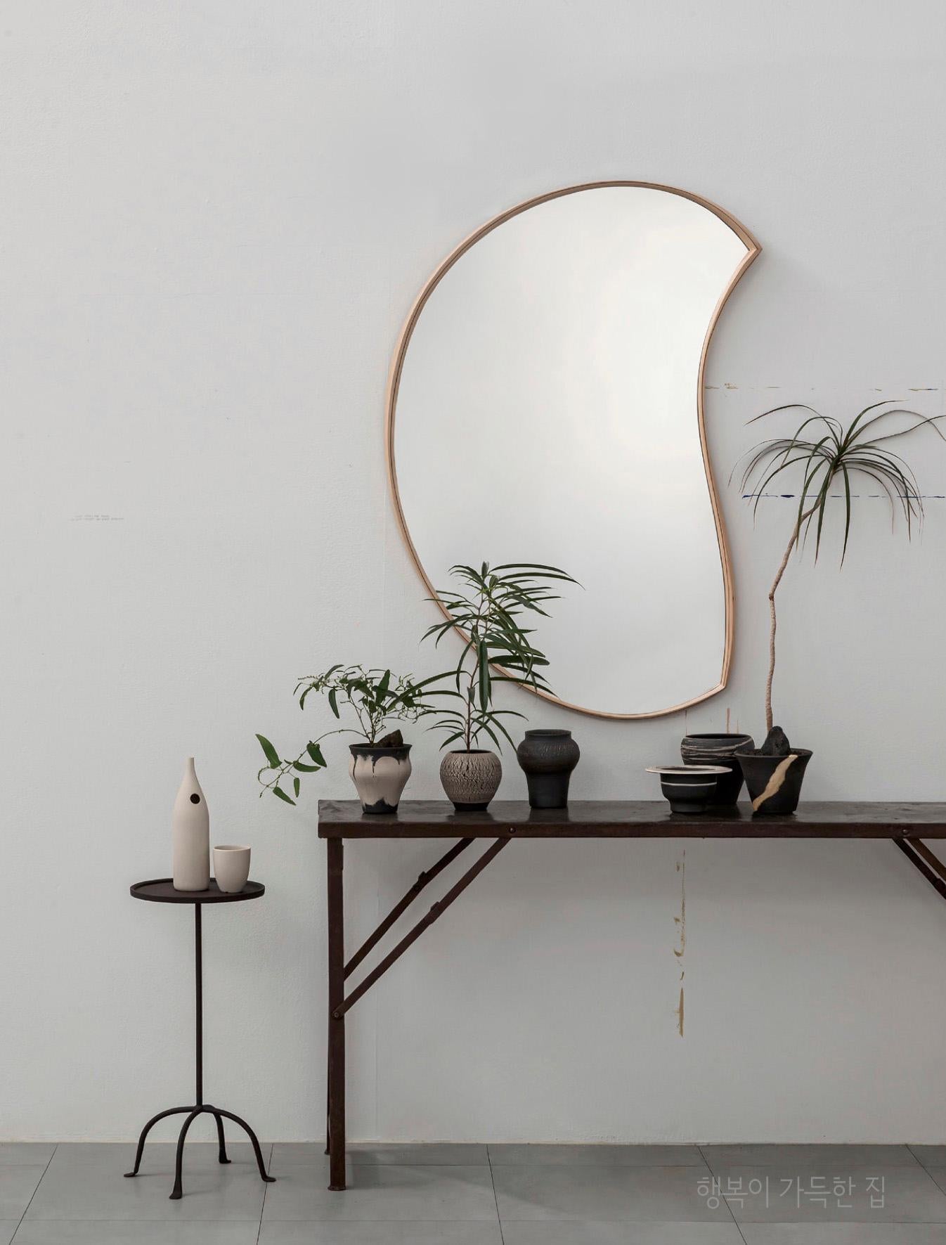 'Moon Mirror' by Soo Joo is an asymmetric and organic wall mirror. It has a timeless beauty that can be enjoyed for decades, and the sculptural work fits into any interior. Soo Joo's works use natural materials that have a long history with mankind,