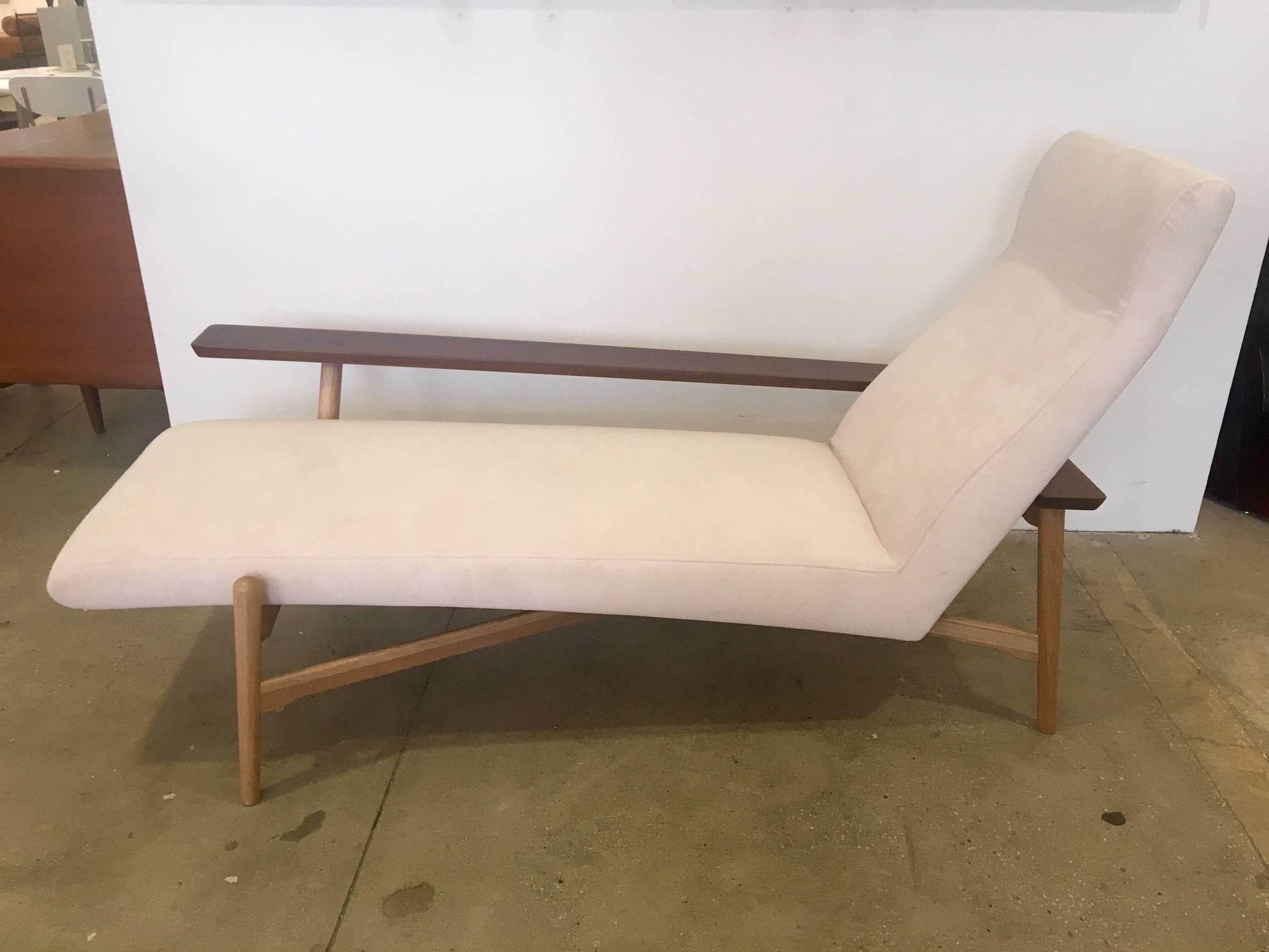 Elegant Mid-Century Modern style chaise longue with asymmetric walnut arm, beech frame and off-white upholstery. Great lines and comfort.