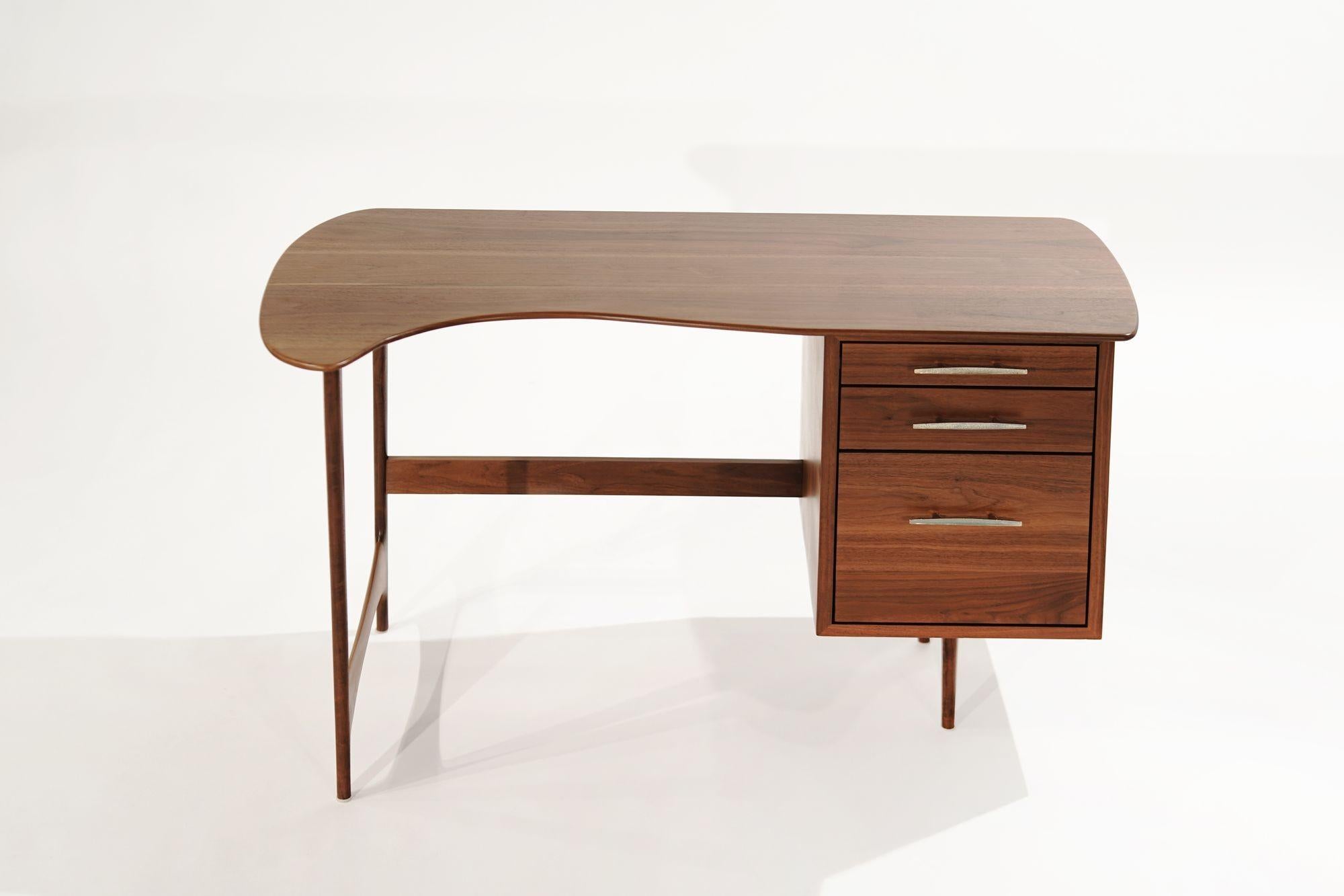 Sculptural walnut desk original from Denmark, circa 1950-1959. Featuring three drawers providing excellent document storage, but the real beauty of this piece is its swooping curves and sudden edges. The impeccable finish highlights the walnut grain