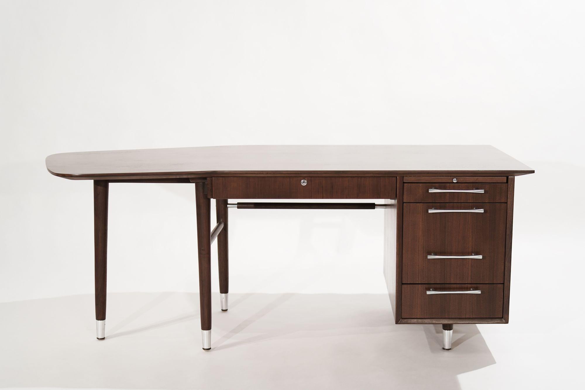 An asymmetric desk executed in walnut, featuring walnut stretchers, nickel hardware, and accents, circa 1950-1959. Completely restored to its original finish, topped with our scratch/water-resistant finish.
 
Other designers from this period