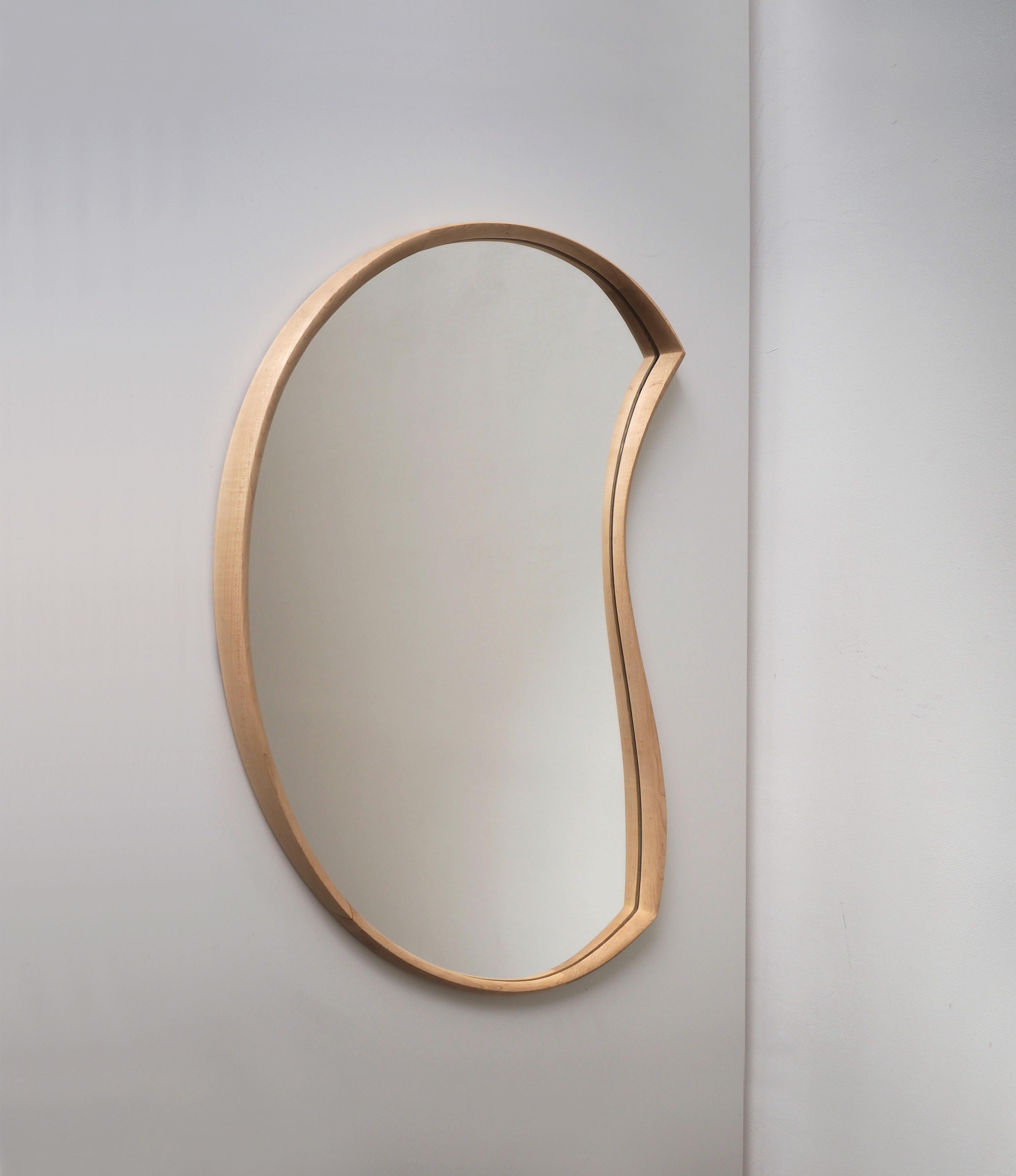 'Moon Mirror' by Soo Joo is a wooden wall mirror with a timeless and asymmetric form. Moon Mirror is hung with a custom-made steel french cleat and hangs flush on the wall. 

This mirror silhouette is minimal but dynamic nature. The undulating thin