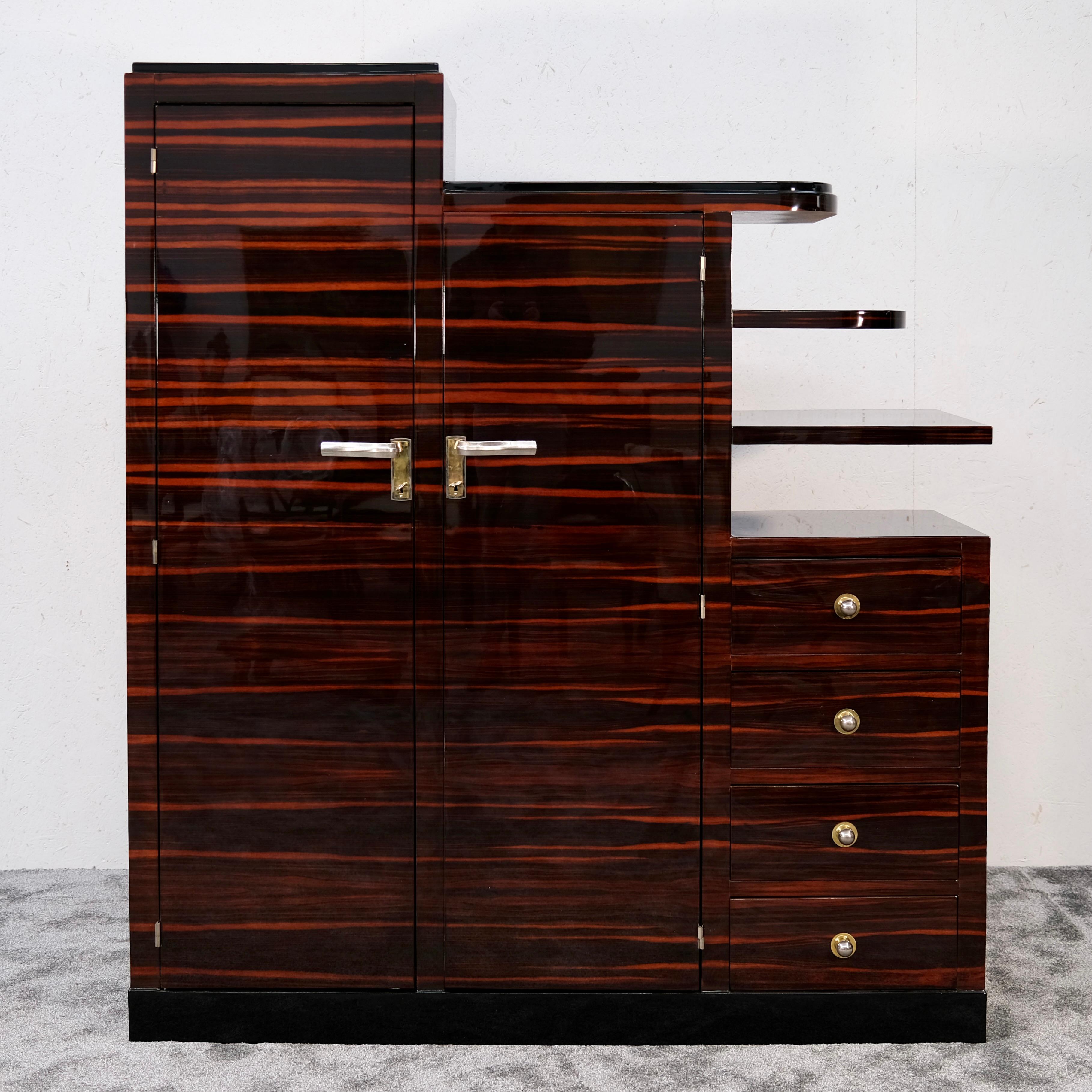 Pièce extraordinaire d'un authentique mobilier Art déco français des années 1930, cette armoire asymétrique incarne l'élégance audacieuse et l'innovation de l'époque. Fabriqué en ébène de Macassar luxueux, sa finition laquée brillante accentue le
